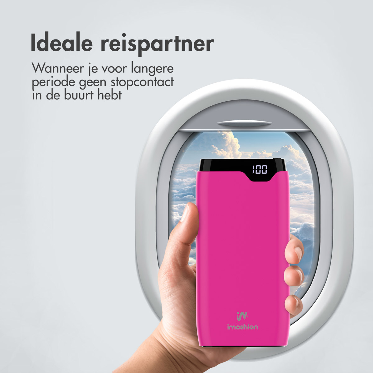 Eine Hand hält eine rosa Powerbank vor einem Flugzeugfenster und zeigt Wolken draußen.