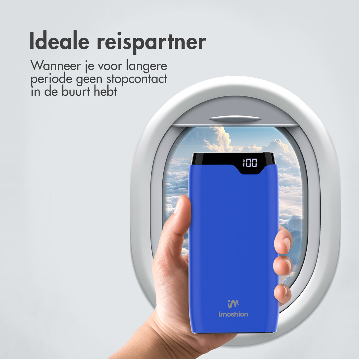Eine Hand hält eine blaue Powerbank vor einem Flugzeugfenster. Die Powerbank zeigt 100 % Ladung an. Text: Idealer Reisepartner.