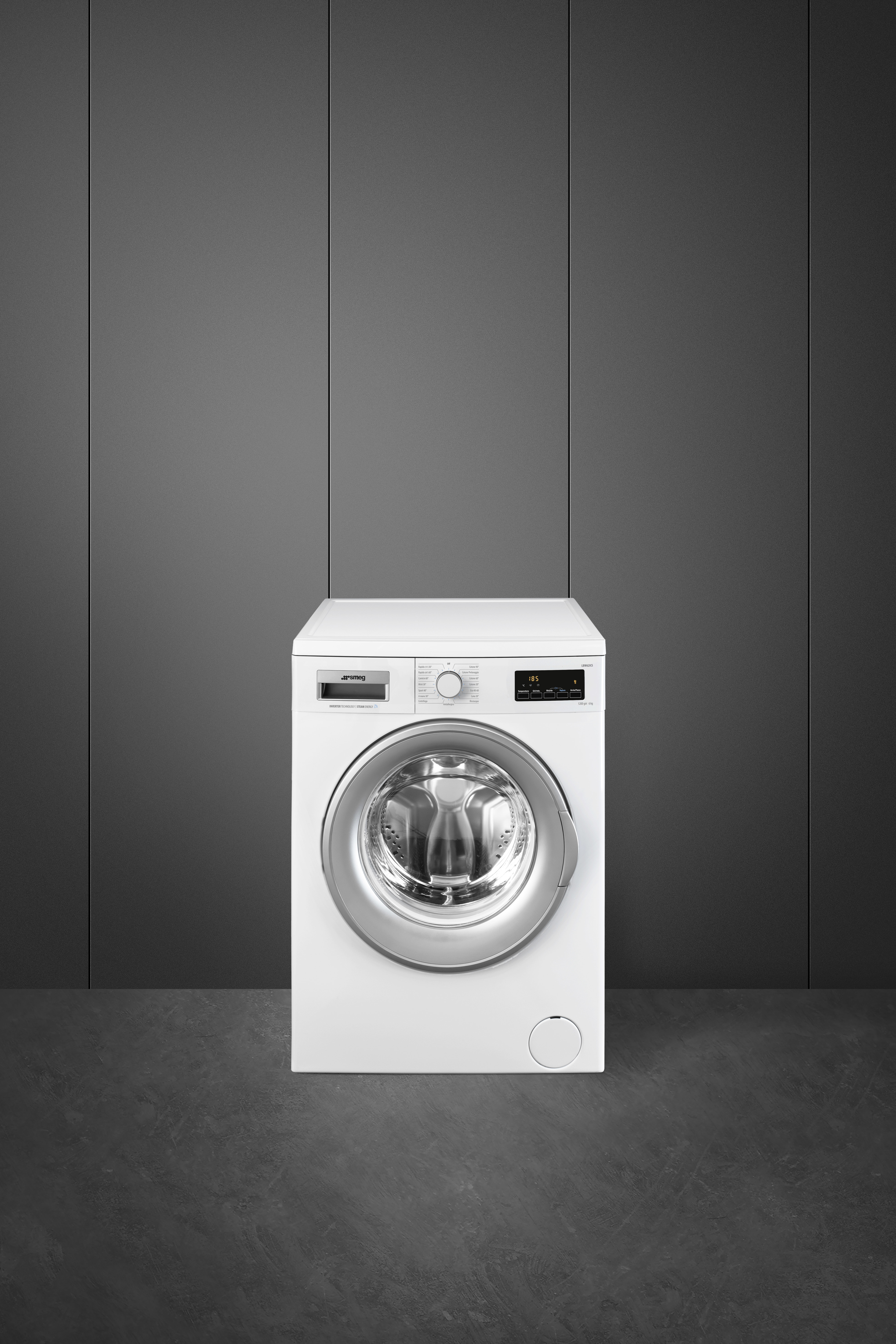 Lavatrice Smeg bianca, centrata in una stanza grigia, con sfondo grigio scuro.