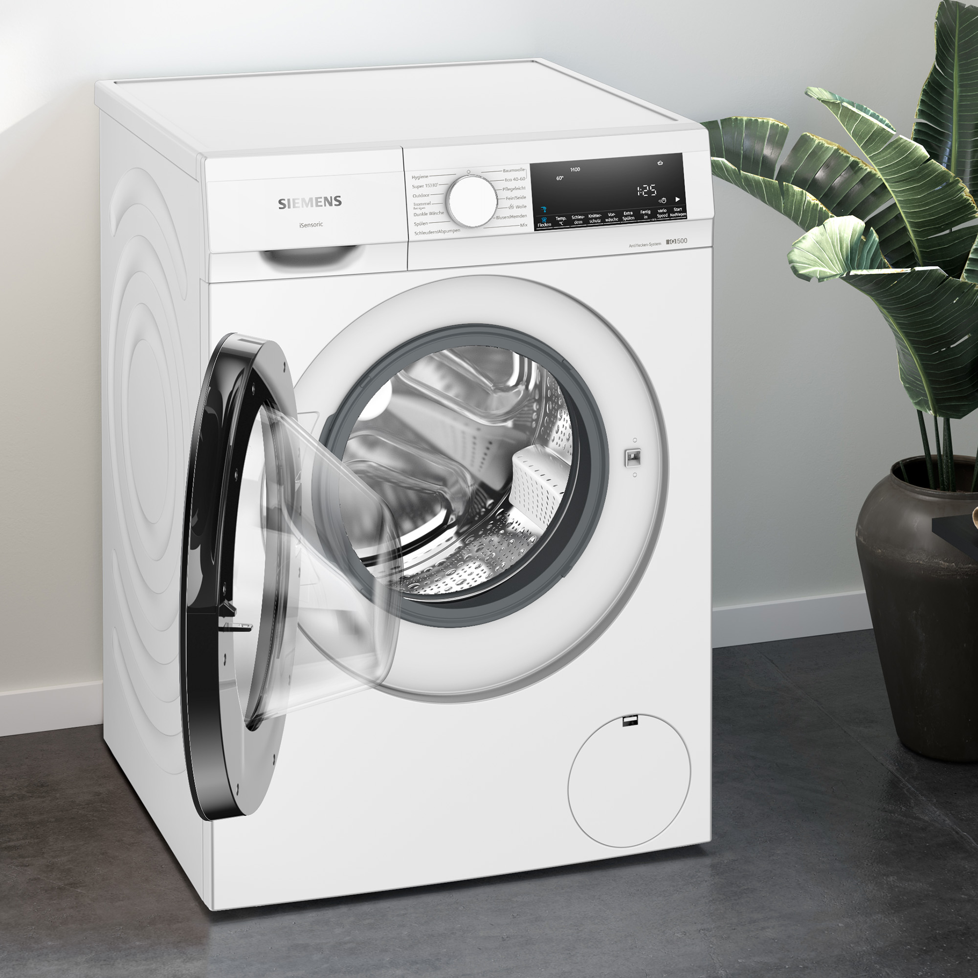 Biała pralka z otwartymi drzwiami, pokazująca bęben. Roślina w tle.