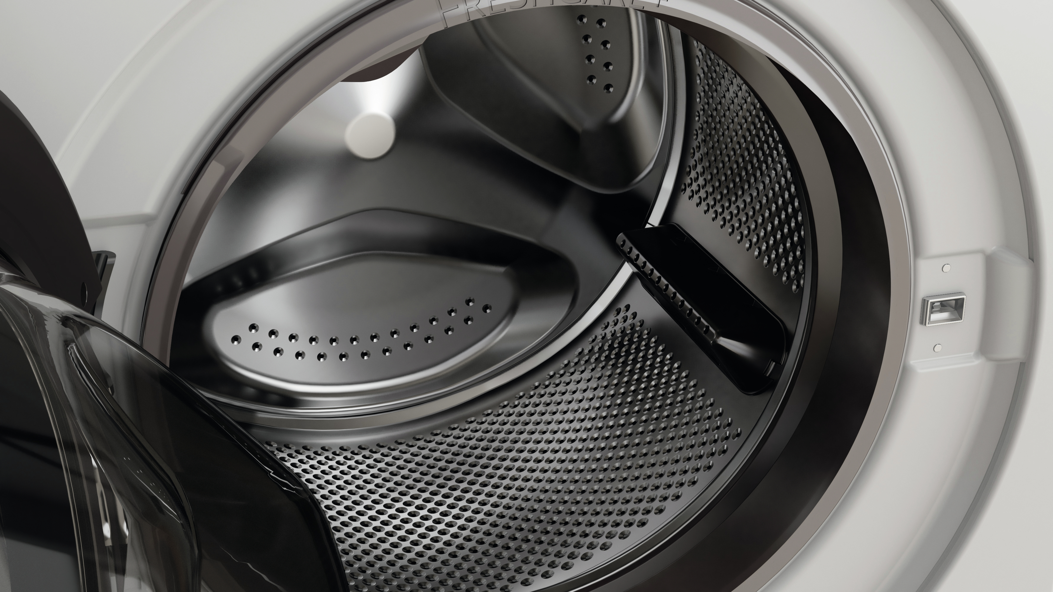 Primo piano dell'interno del cestello di una lavatrice, che mostra la superficie perforata e il design.