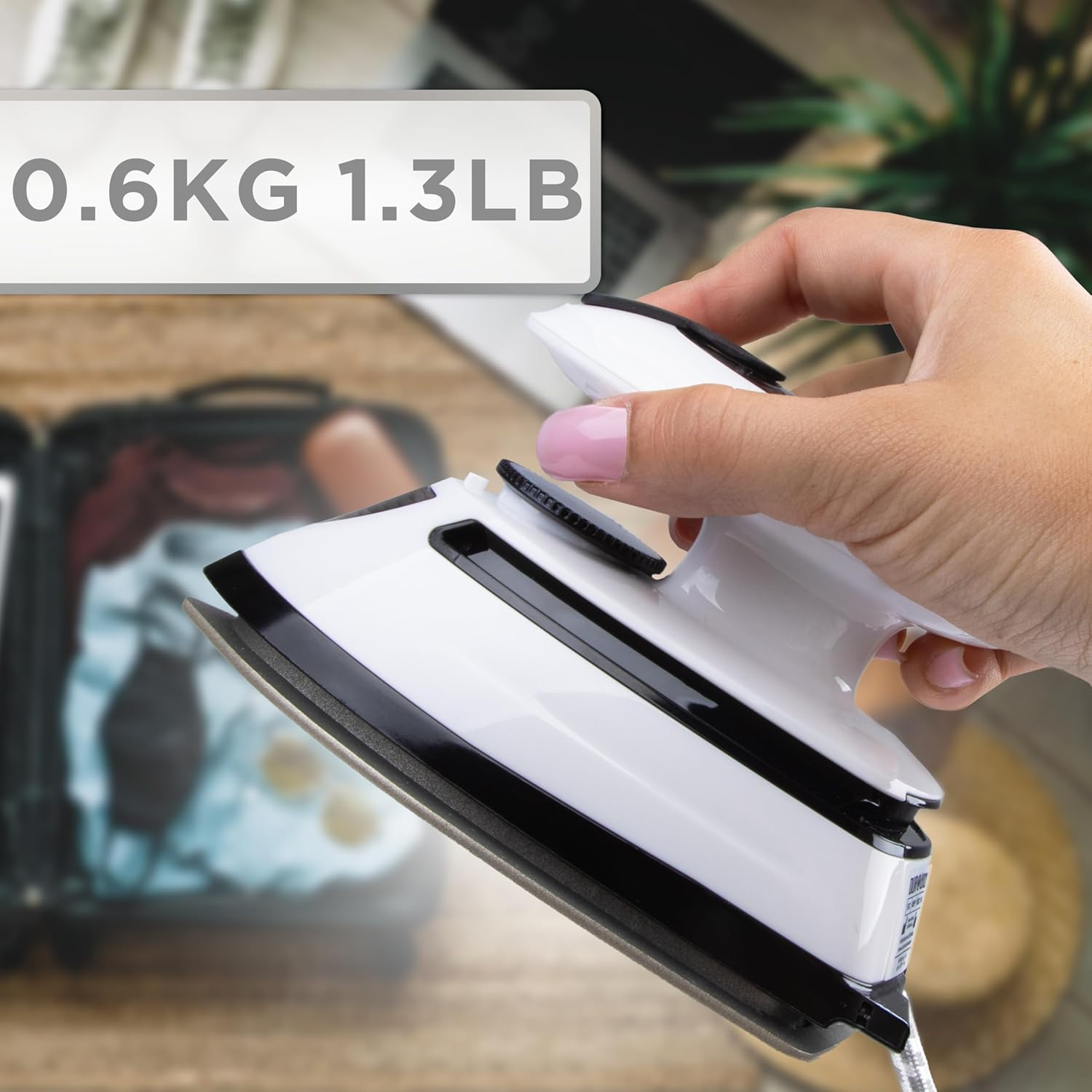Hand, die ein weißes Bügeleisen hält, mit einem Gewichtslabel von 0,6 kg/1,3 lb.