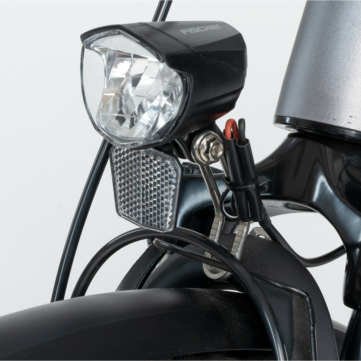 Nahaufnahme eines Fahrradlichts mit Reflektor und schwarzen Kabeln.