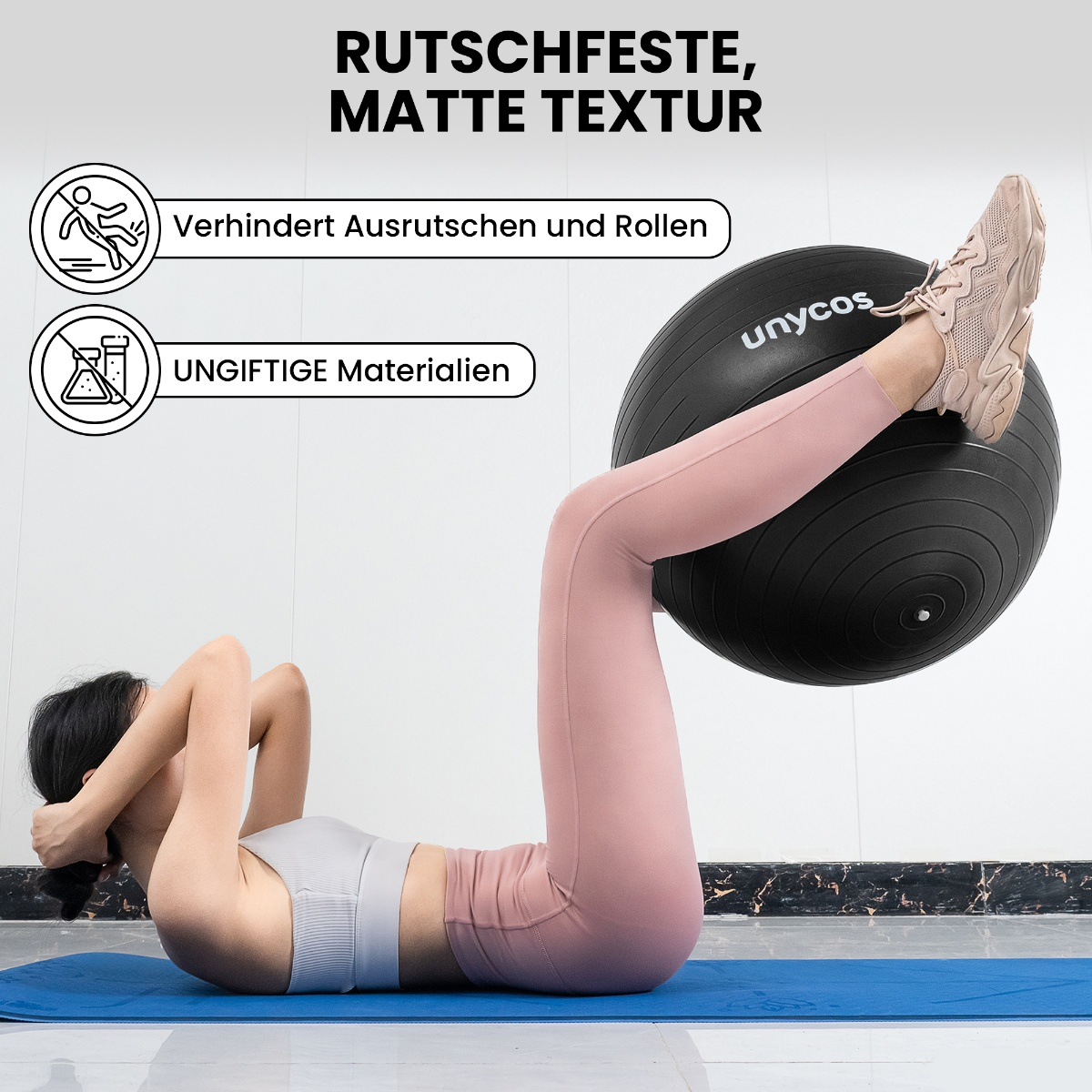 Eine Frau auf einer blauen Matte macht Sit-ups mit einem schwarzen Gymnastikball zwischen den Beinen.