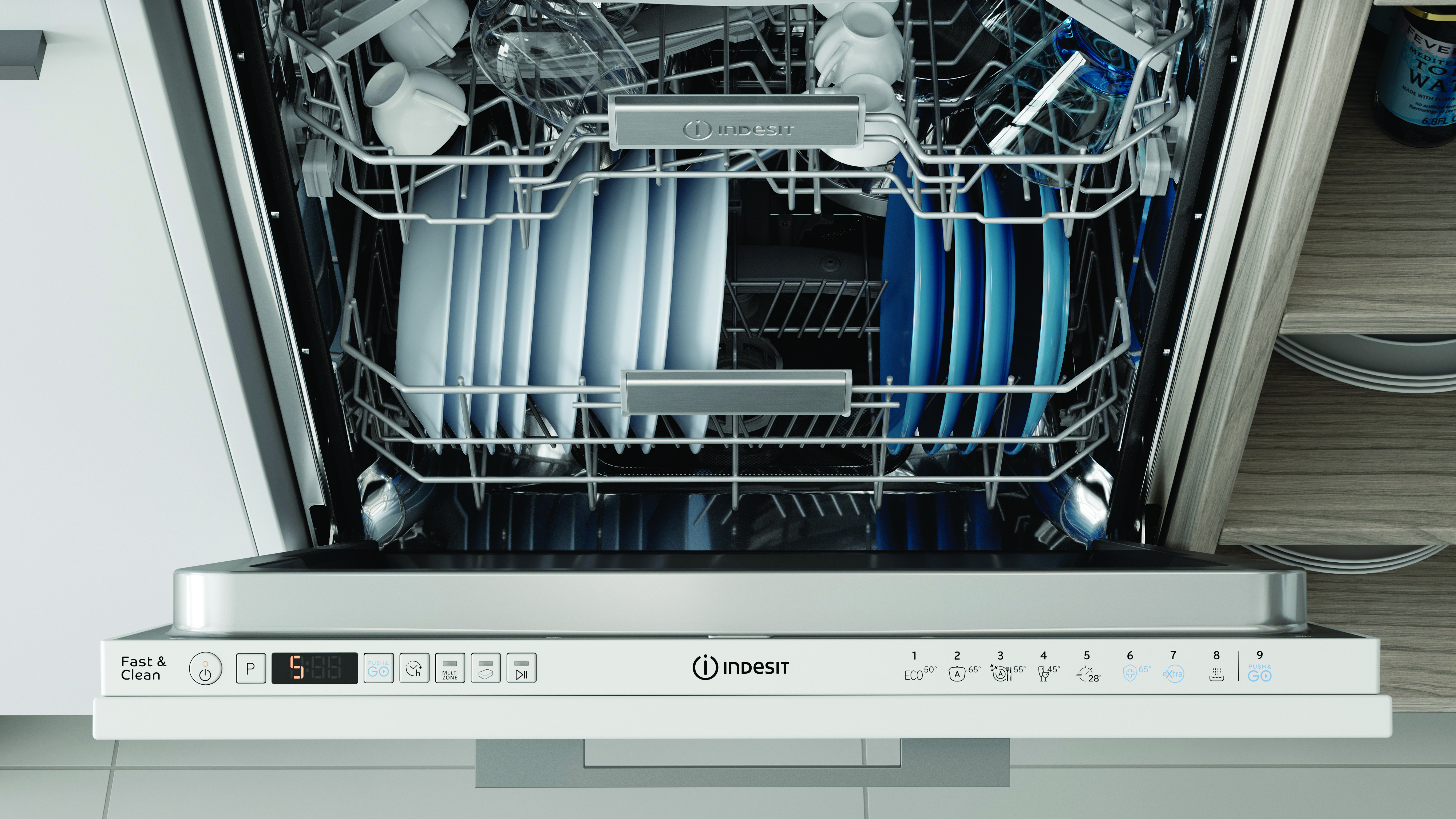 Interno lavastoviglie con piatti e bicchieri. Marchio Indesit, con pannello bianco.