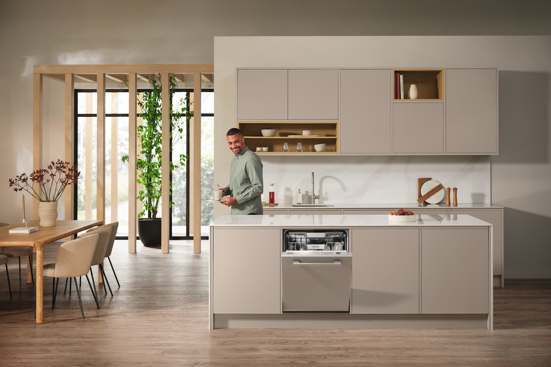 Küchenszene mit Mann in der Nähe einer Spülmaschine. Kücheninsel mit offener Spülmaschine. Modernes Design.