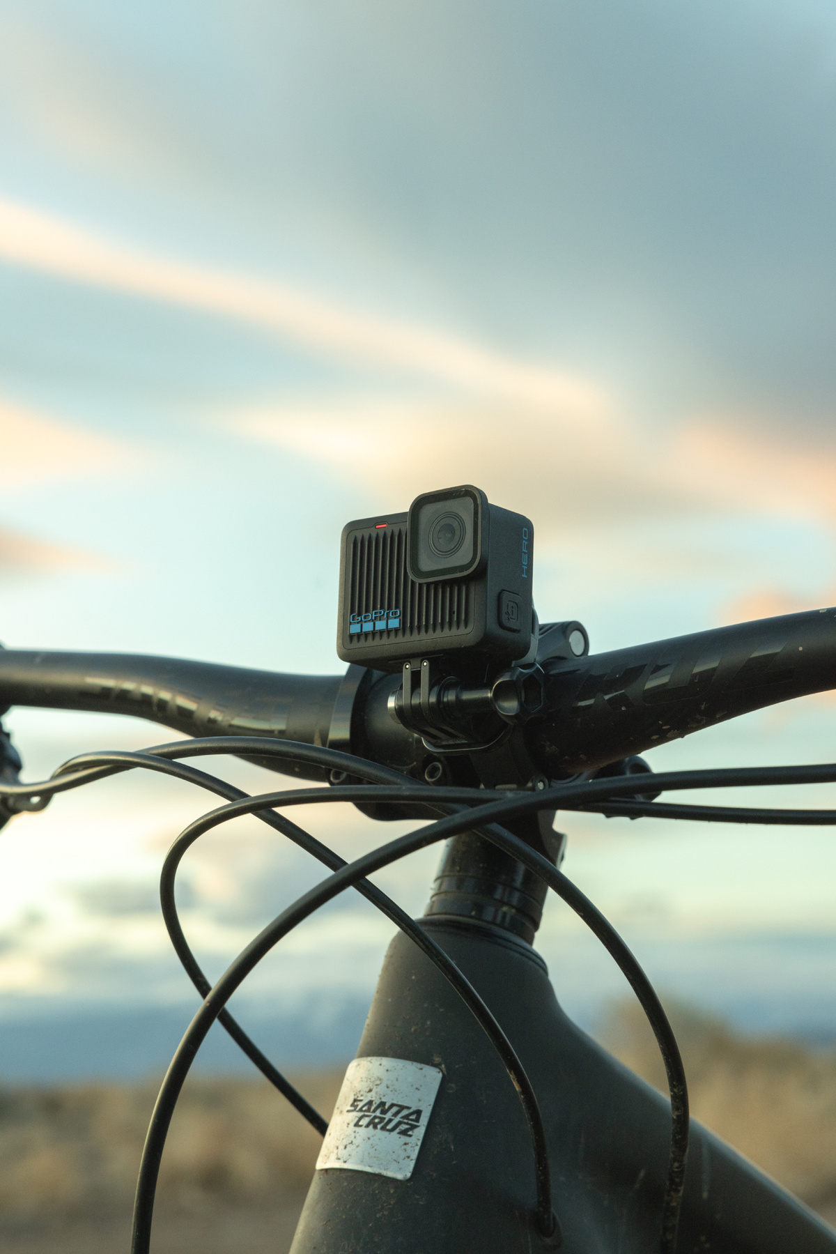 Una cámara GoPro montada en el manillar de una bicicleta de montaña, con un cielo nublado de fondo.