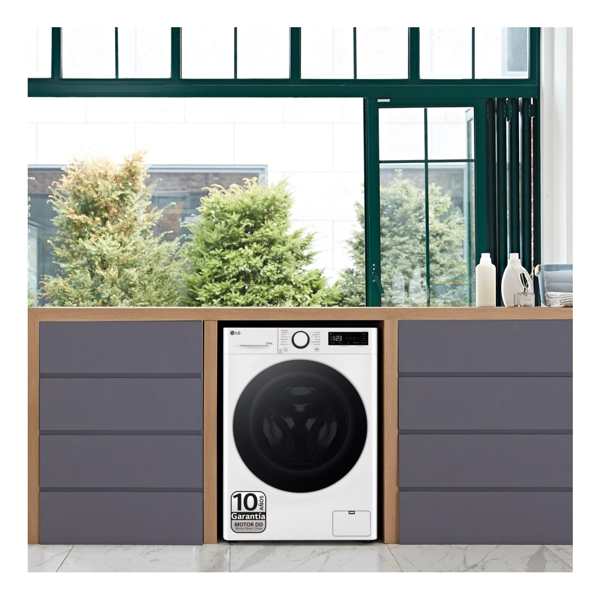 Biała pralka wbudowana w szafkę, z oknem i roślinami w tle.