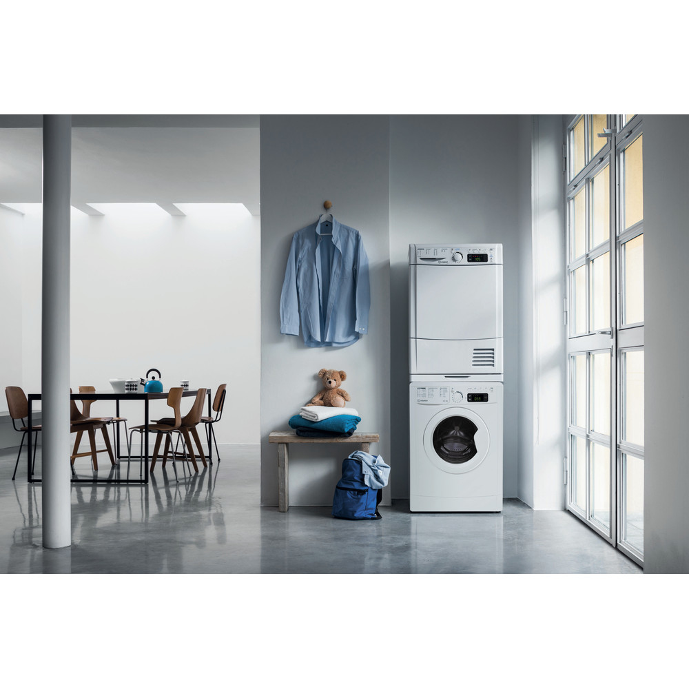 Una habitación con lavadora y secadora, con otros elementos como una mesa y una camisa azul.