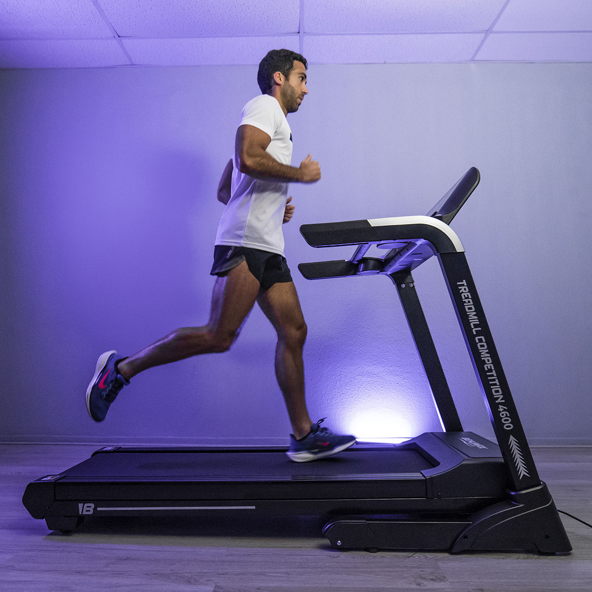 Hombre corriendo en una cinta de correr. La cinta es negra y tiene una pantalla digital.