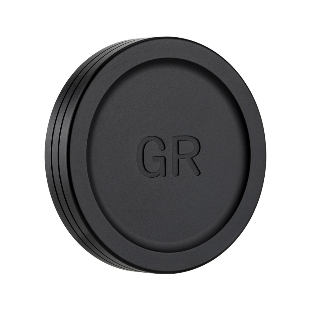 Schwarzer Objektivdeckel mit geprägtem 'GR'-Text. Es ist ein kreisförmiges Objekt, weißer Hintergrund.