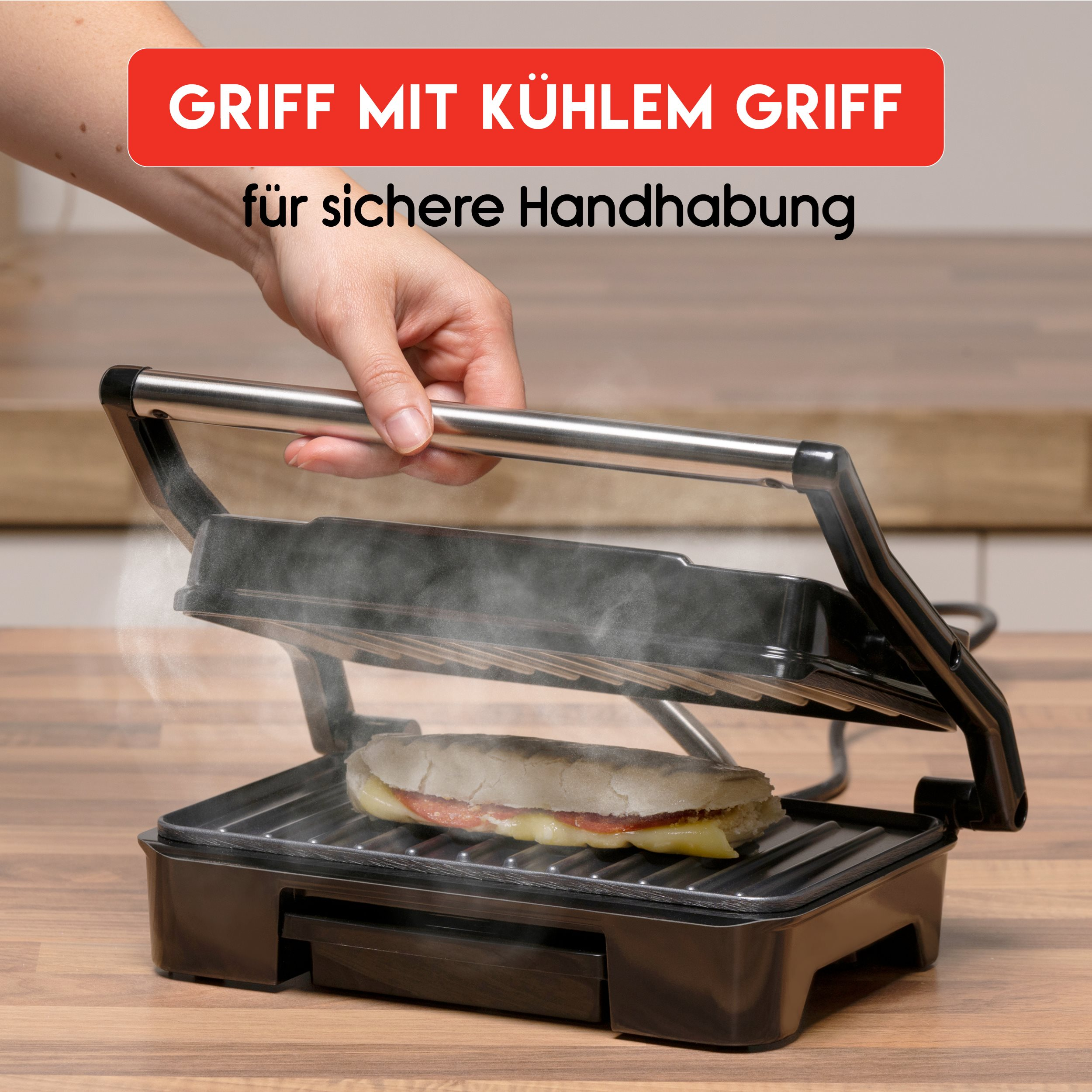 A black panini press with a sandwich inside, being held by a hand.