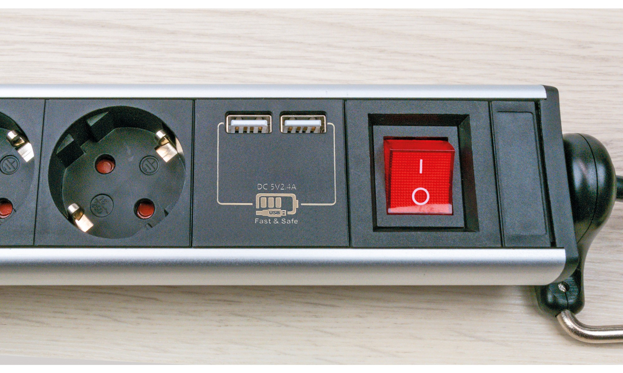 Steckdosenleiste mit drei Steckdosen, zwei USB-Anschlüssen und einem roten Netzschalter. Weißer Hintergrund.