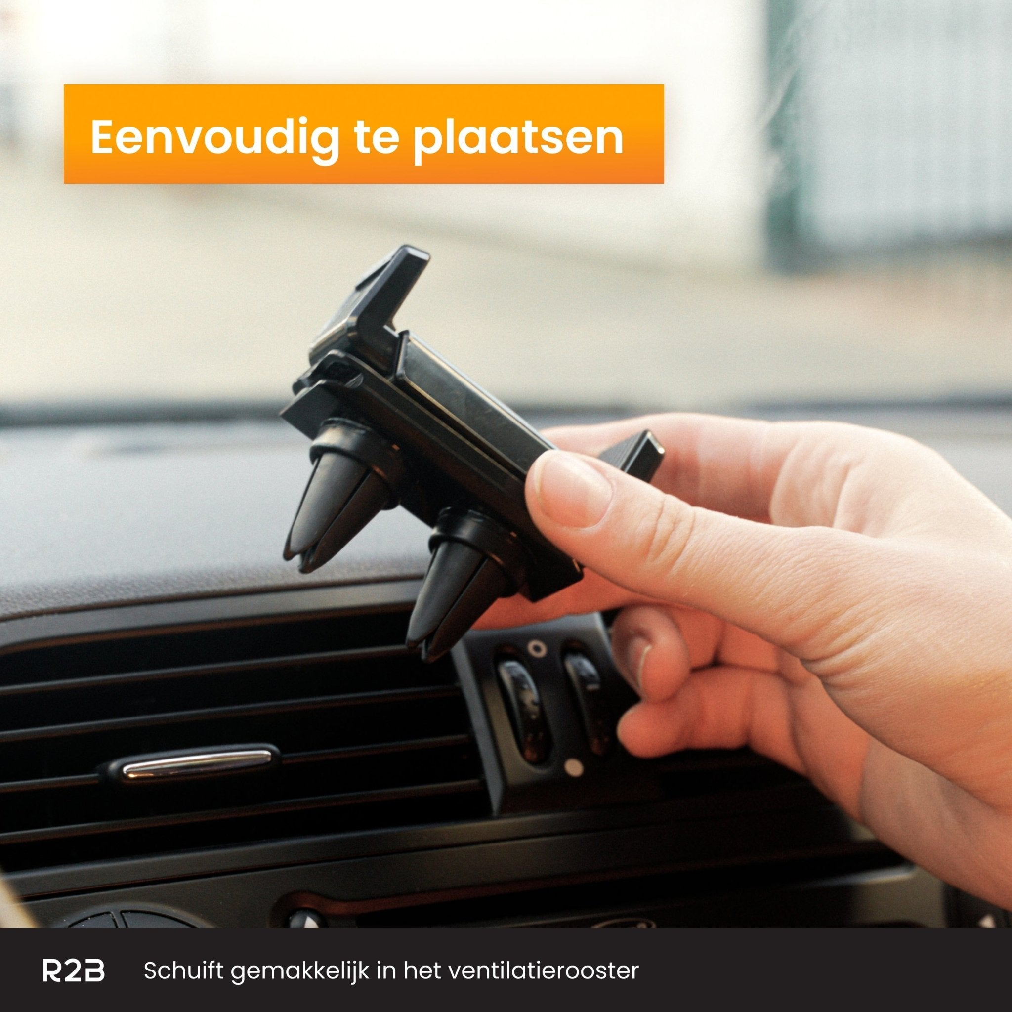 Een hand plaatst een zwarte telefoonhouder voor in de auto in het ventilatierooster van een auto. De houder heeft verstelbare pinnen.