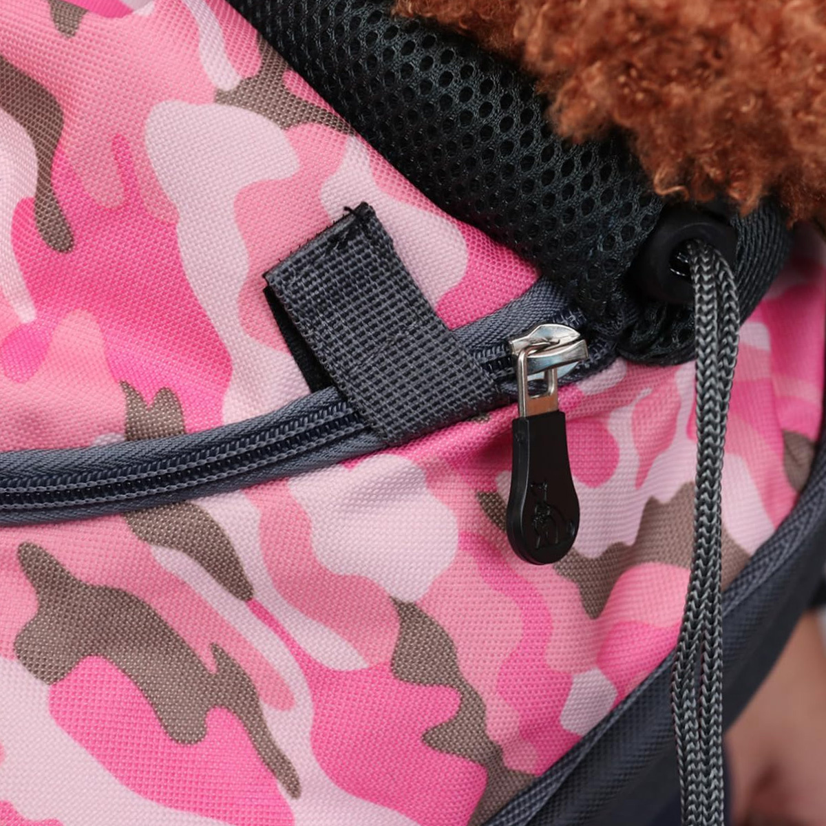 Nahaufnahme einer pinkfarbenen Tarnung-Haustiertasche mit schwarzem Reißverschluss und Hund.