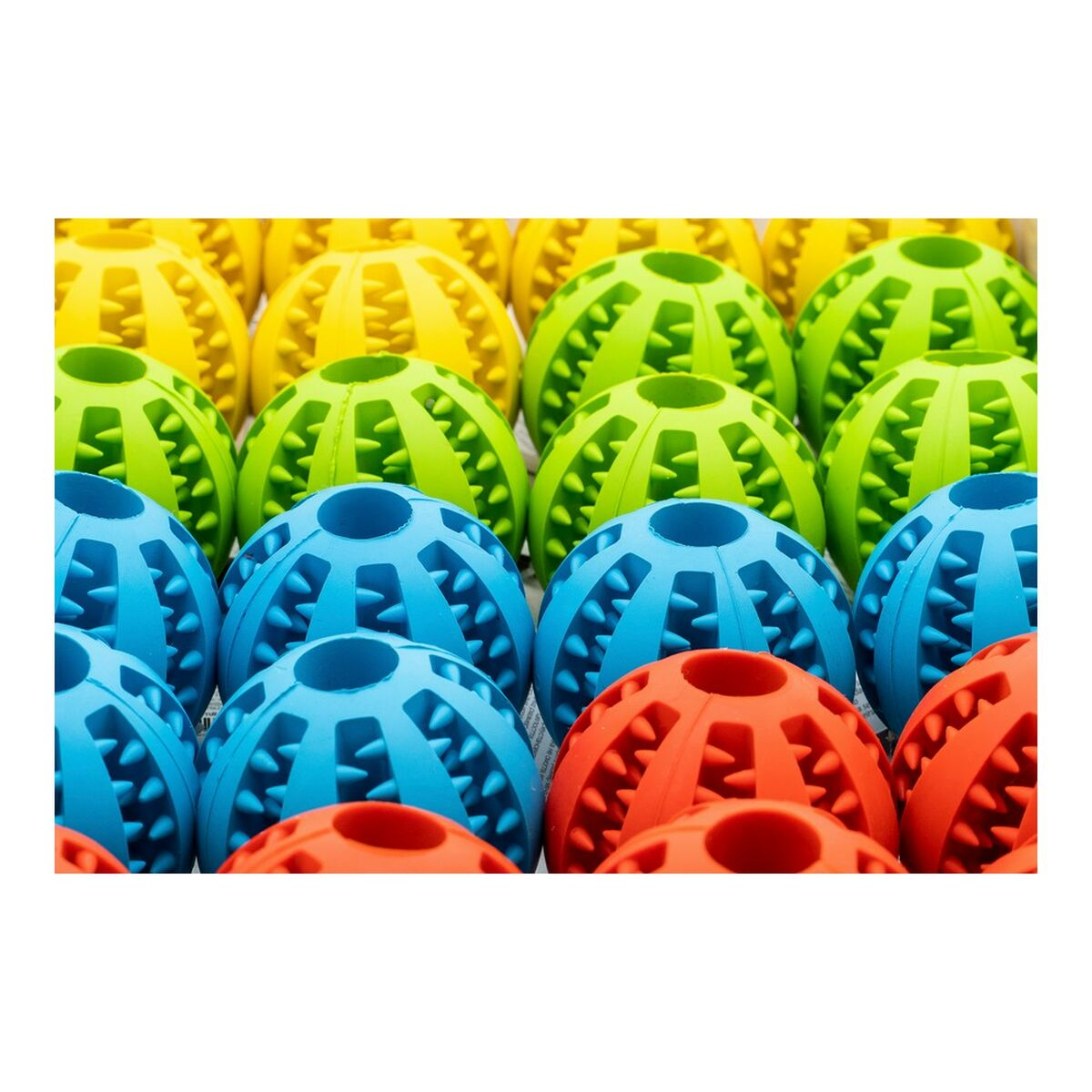 Mehrere bunte Hundespielzeuge in einer Reihe. Gelb, grün, blau und rot. Alle haben die gleiche Form.