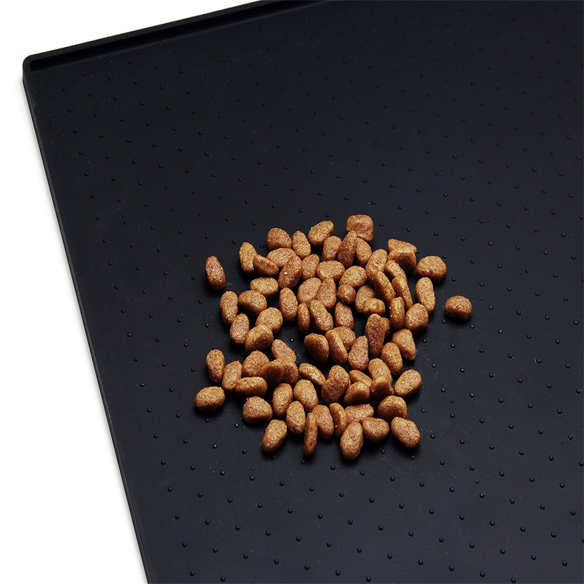 Eine schwarze Matte bedeckt mit braunen Trockenfutter. Die Matte hat kleine, erhabene Unebenheiten.