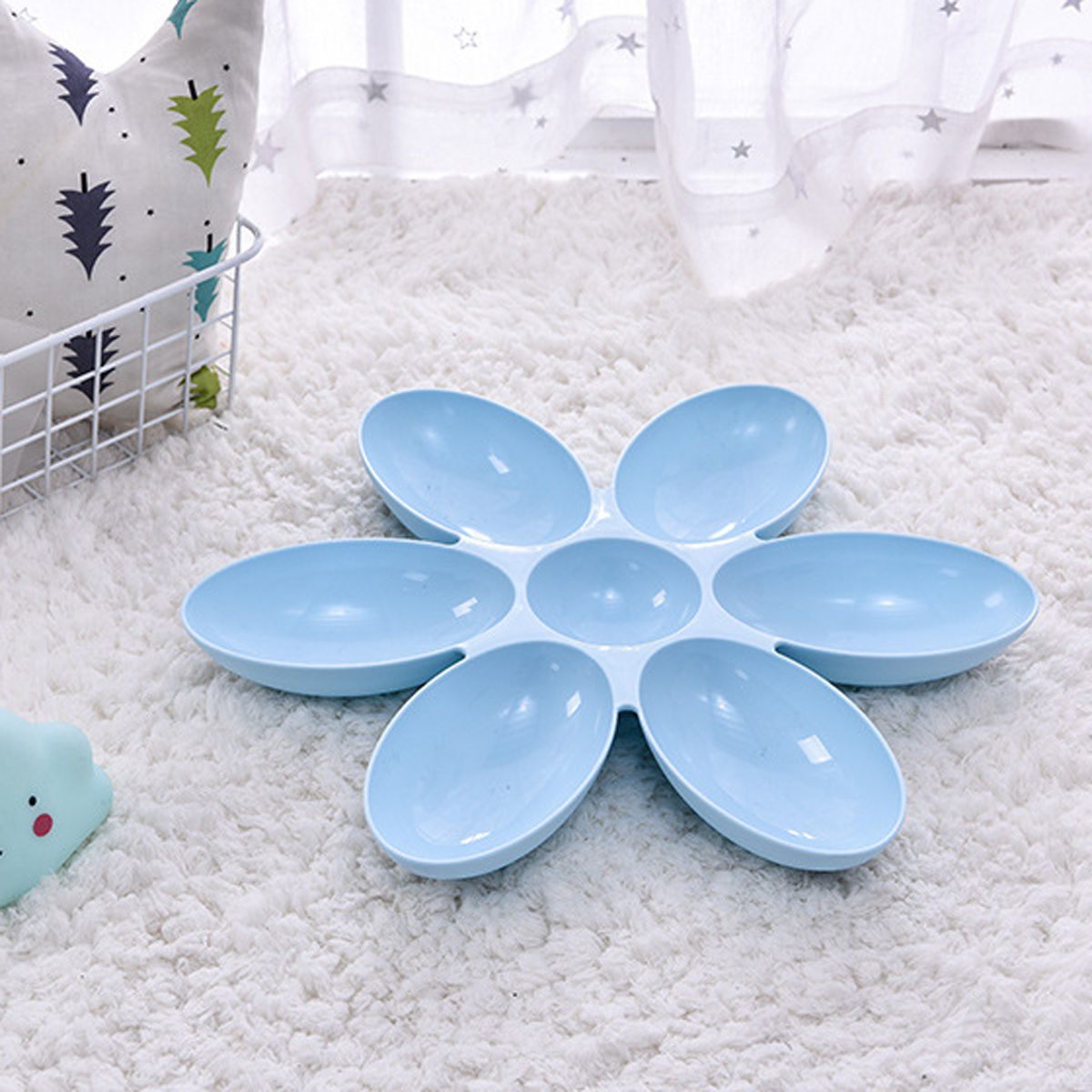 Blaue, blütenförmige Haustierschüssel auf einem weißen, flauschigen Teppich. Weißer Hintergrund.