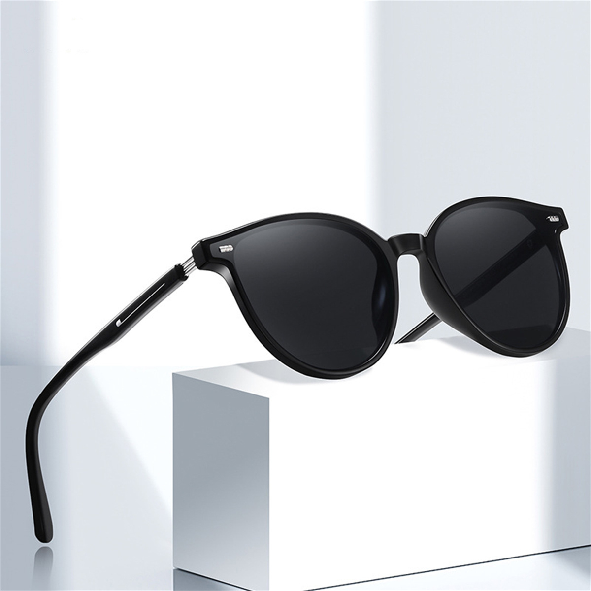 Schwarze Sonnenbrille auf weißer Oberfläche, mit Seitenansicht, die ihr Design und ihre Form zeigt.