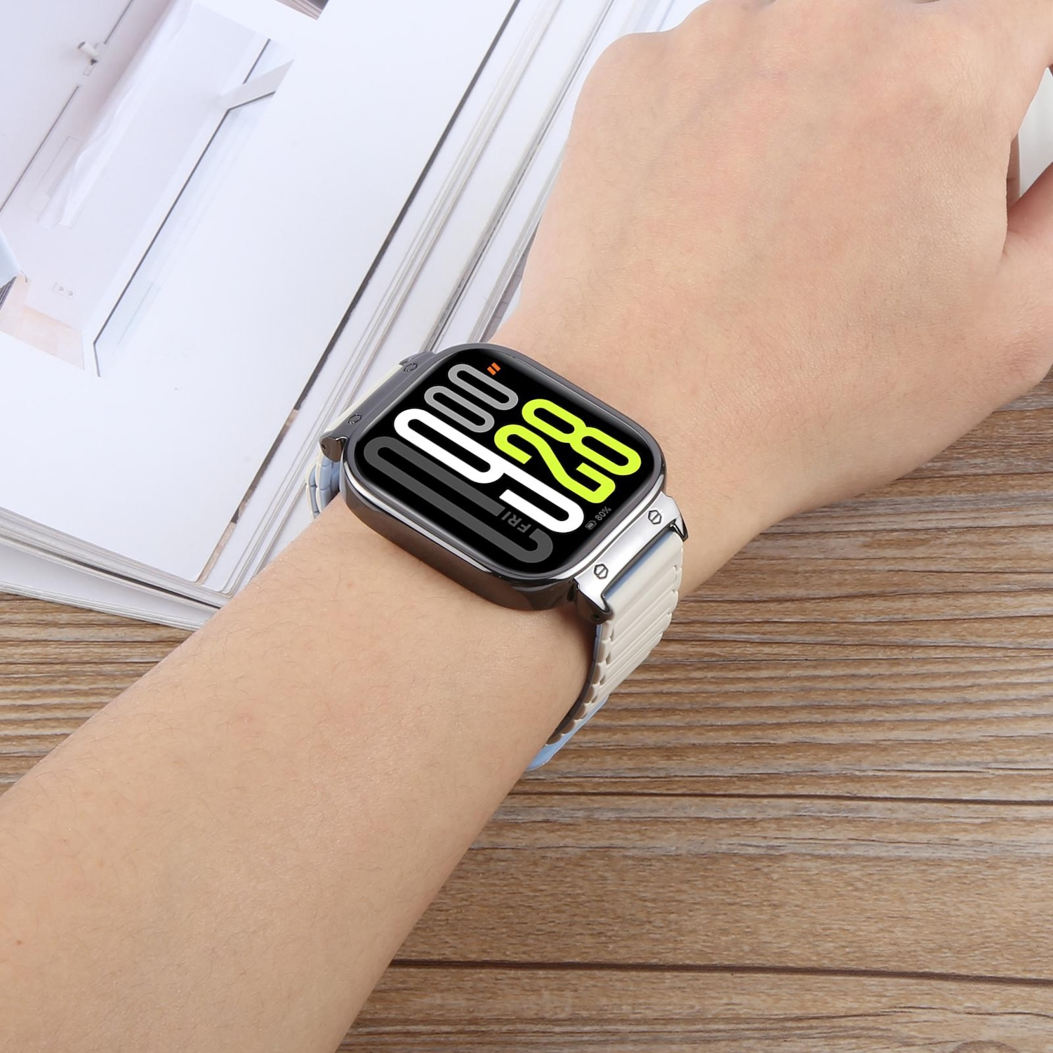 Handgelenk einer Person mit einer Smartwatch. Die Uhr hat ein helles Armband.
