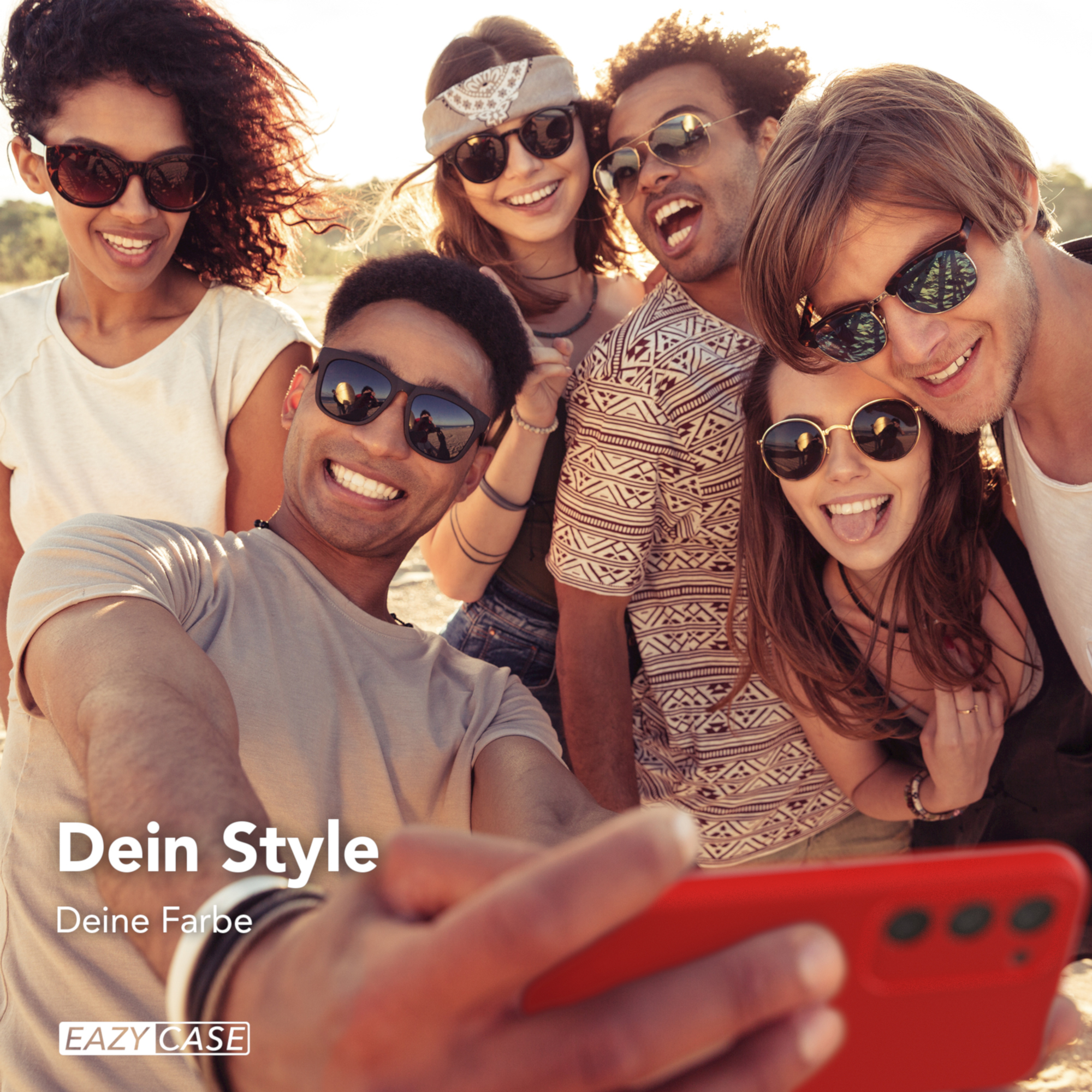 Gruppe von Leuten macht Selfie mit rotem Telefon. Sie lächeln. Der Hintergrund ist sonnig.