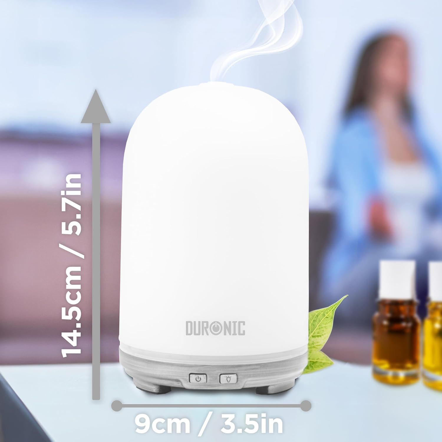 Weißer Aroma-Diffusor mit Maßen, Frau im Hintergrund.