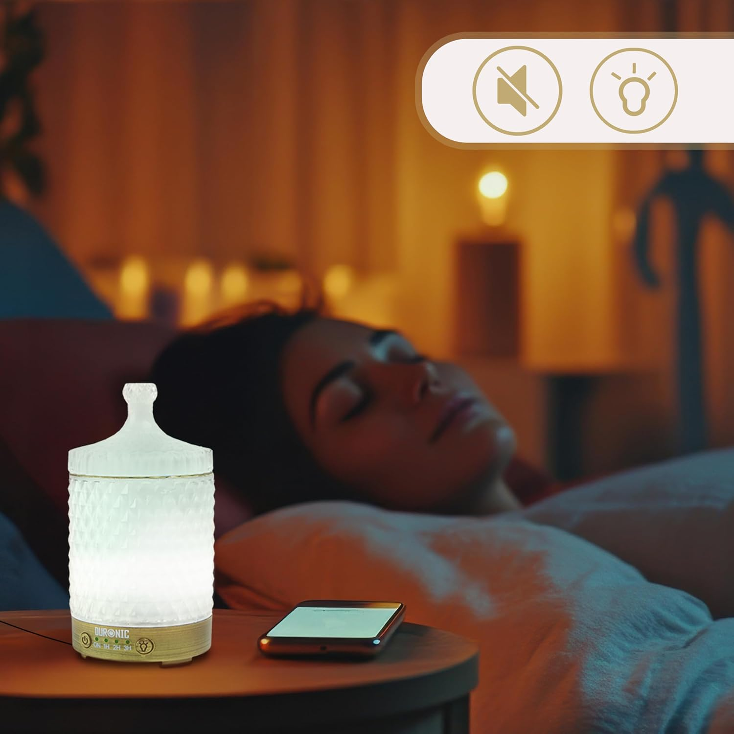 Eine Frau schläft neben einem Diffusor für ätherische Öle und einem Telefon auf einem Nachttisch. Der Raum ist schwach beleuchtet.