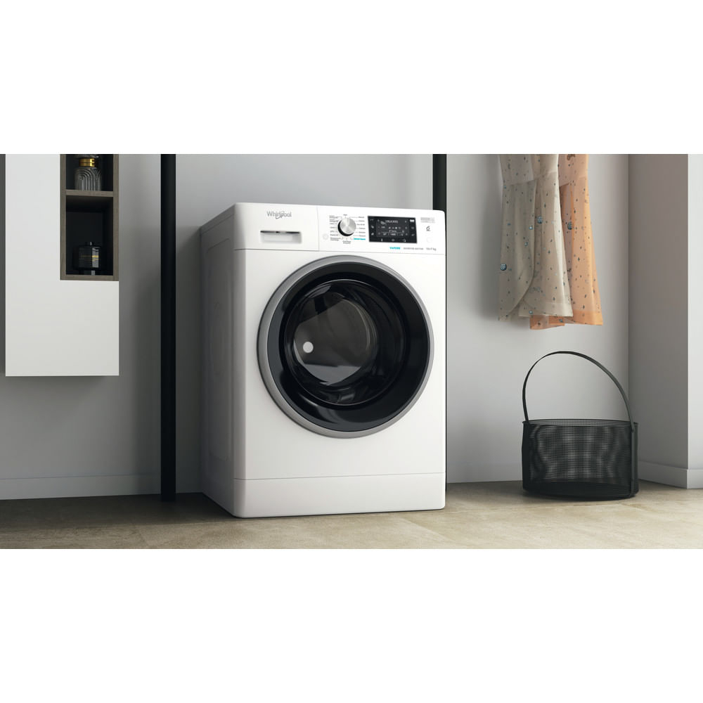Una lavatrice Whirlpool bianca con porta nera, vicino a una borsa nera e vestiti appesi.