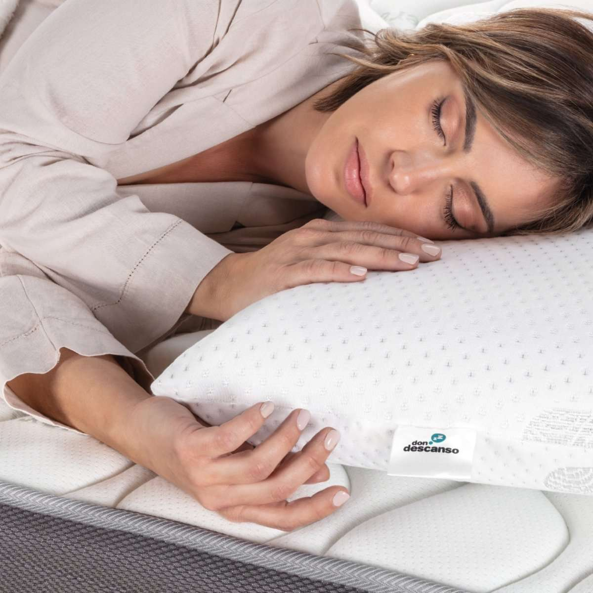 Una mujer durmiendo en una almohada blanca con la etiqueta 'don descanso'.