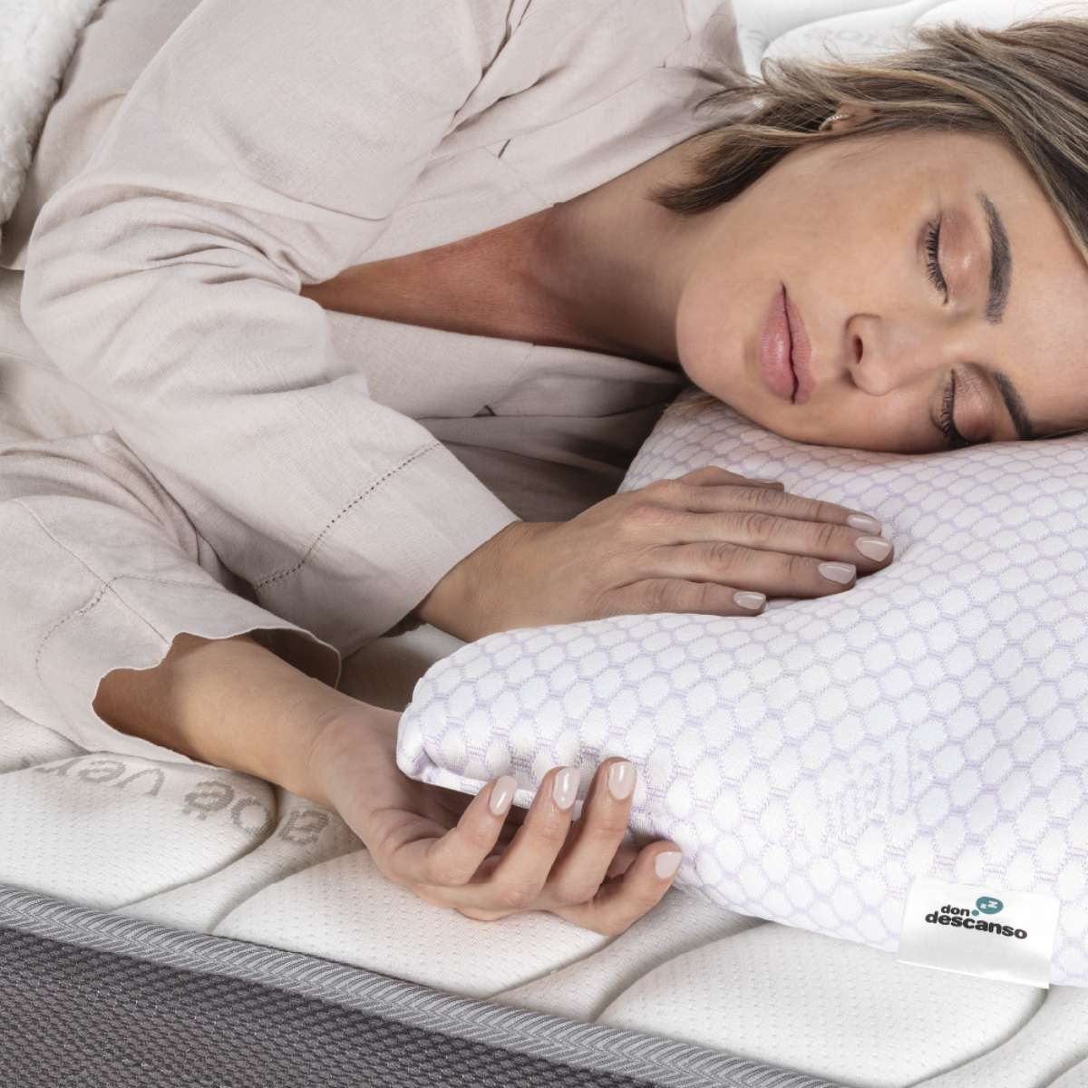 Mujer durmiendo en una cama, cabeza sobre una almohada con patrón de panal.