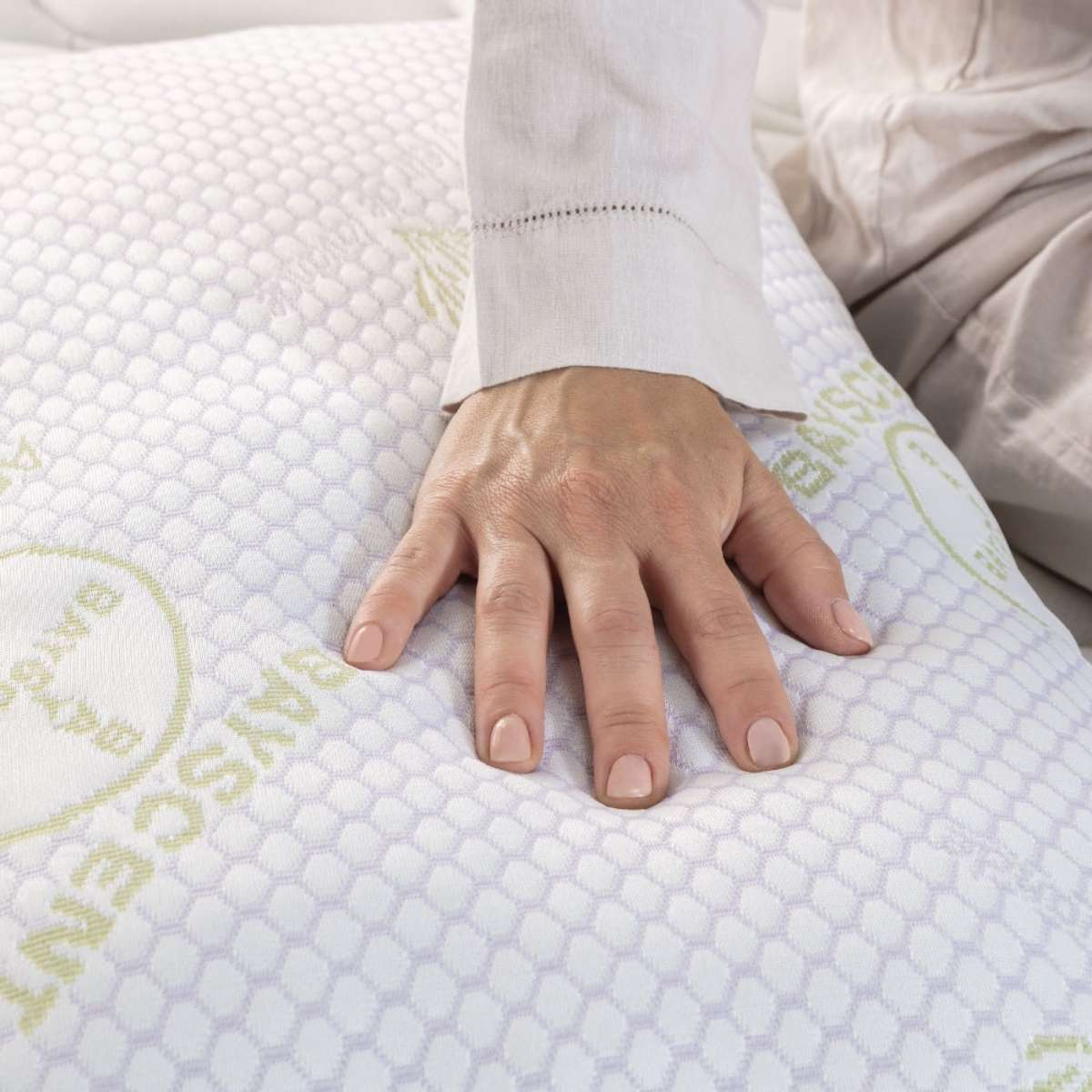 Una mano sobre una almohada blanca. La almohada tiene un patrón de panal.