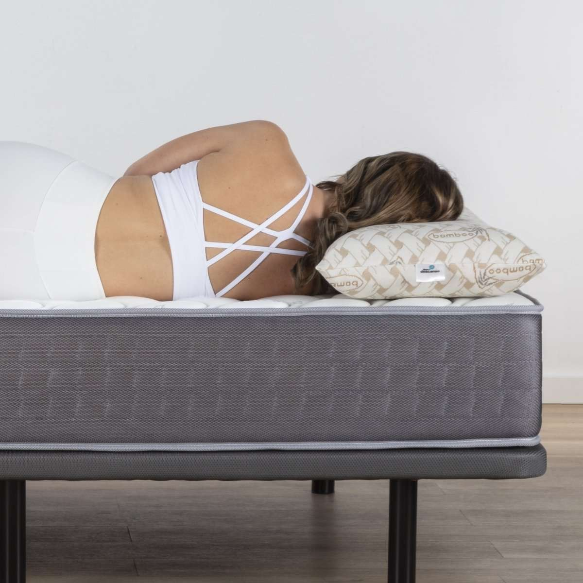 Mujer acostada en un colchón con top blanco. Una almohada bajo su cabeza.
