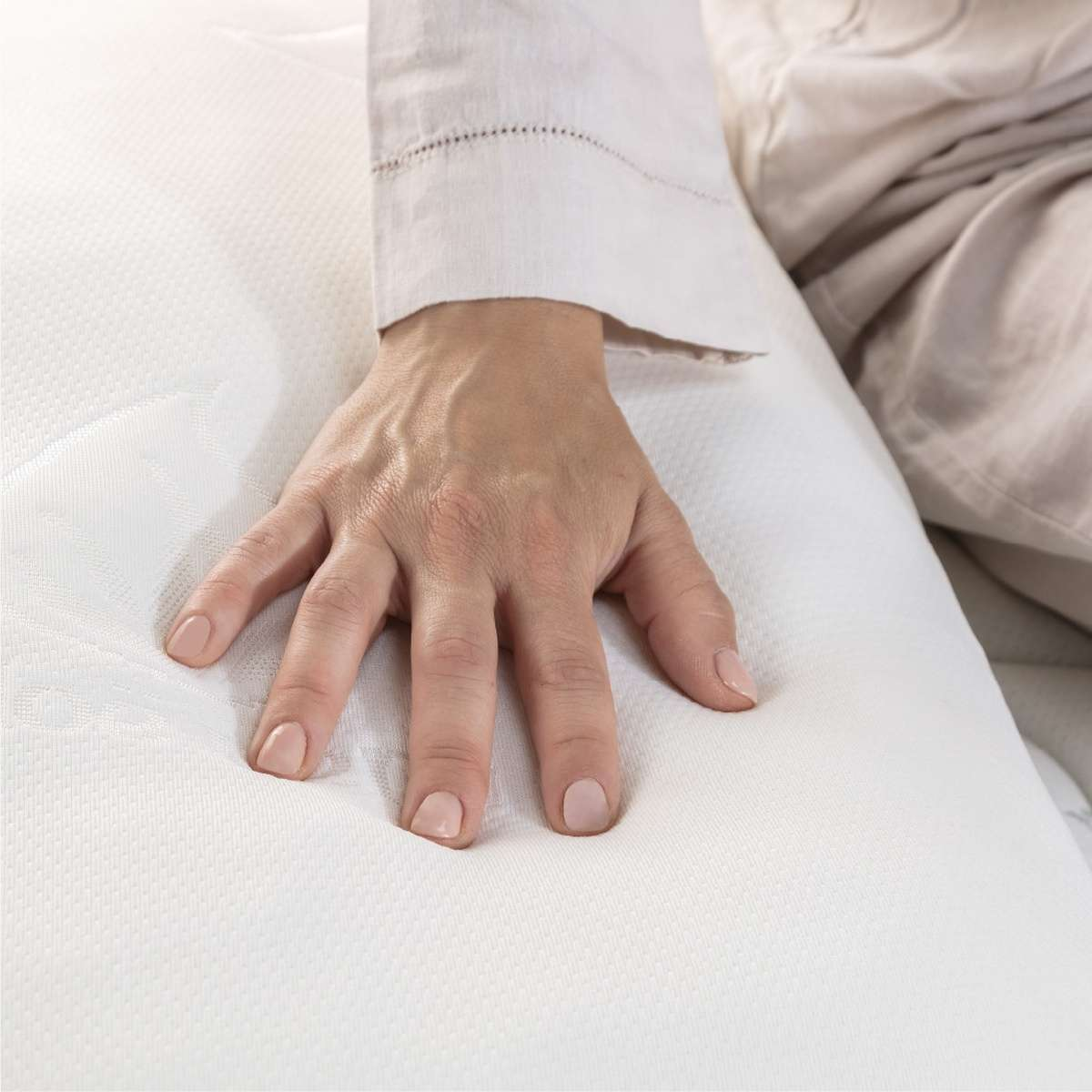 Una mano presiona un colchón blanco, mostrando una superficie suave y cómoda.