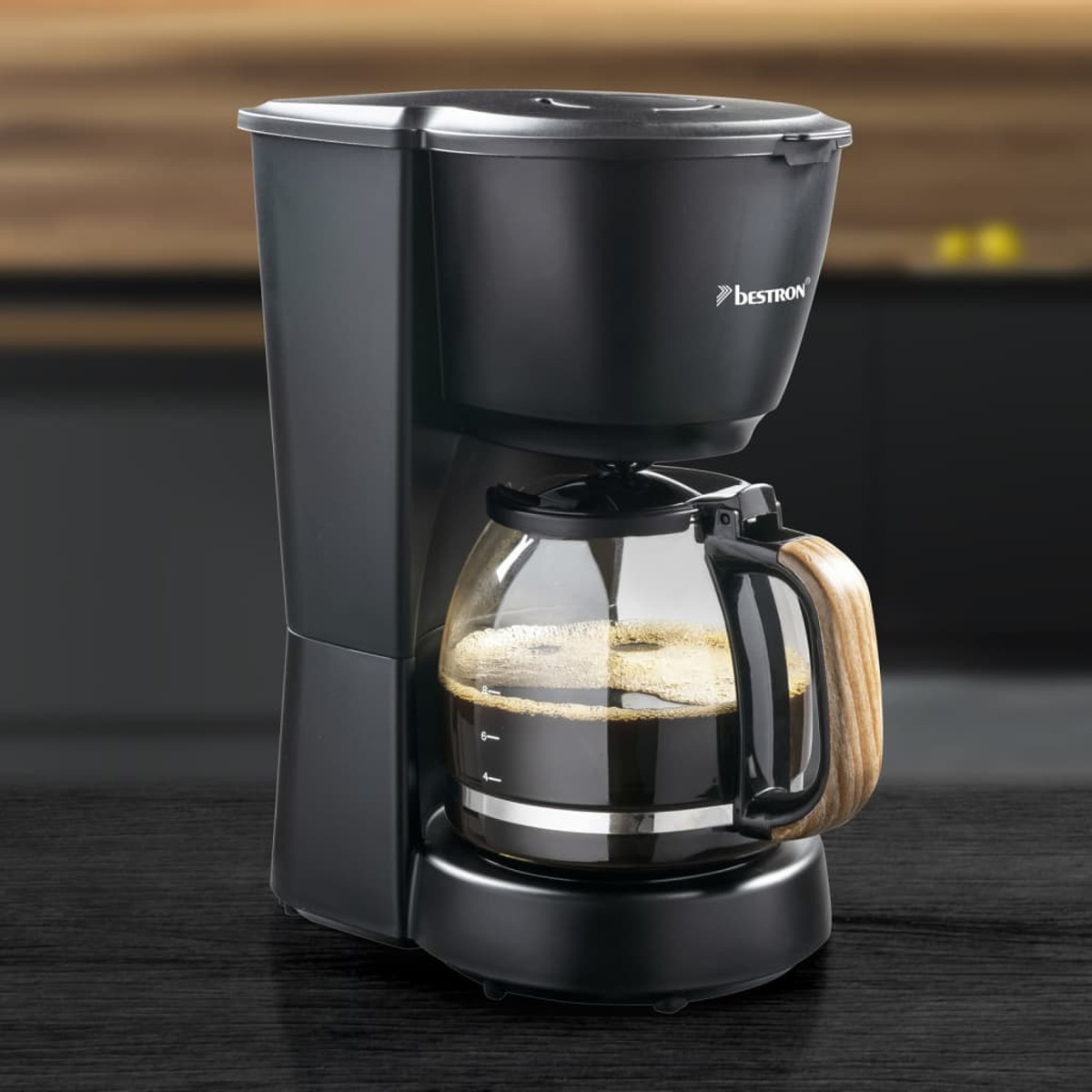 Czarny ekspres do kawy ze szklaną karafką i drewnianym uchwytem. Marka to Bestron.