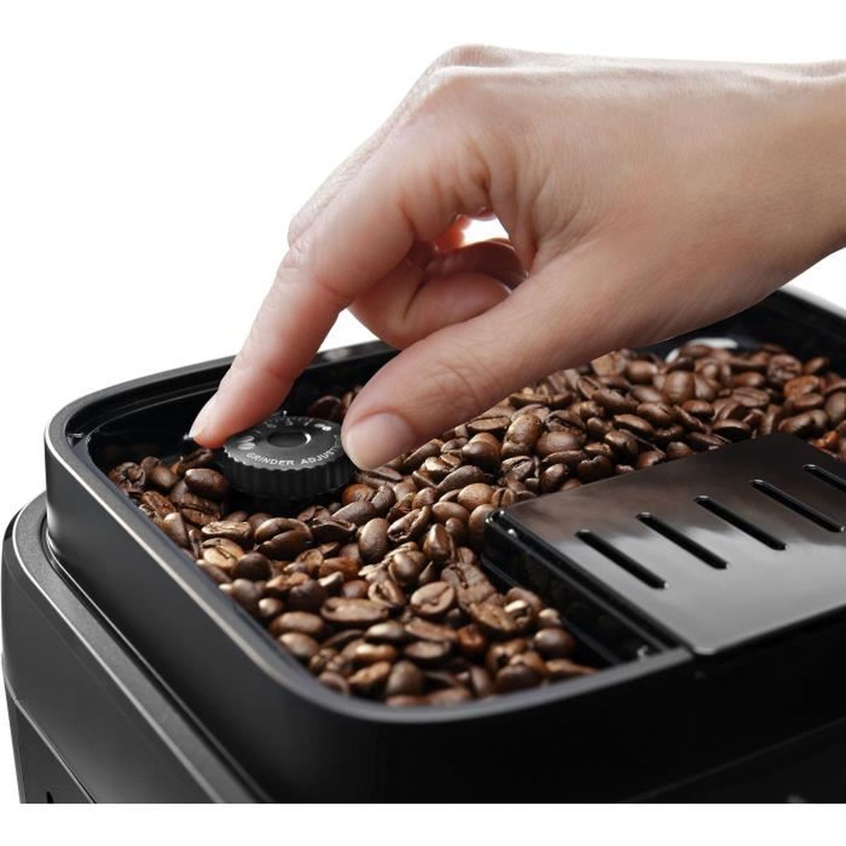 A hand adjusting a dial on a coffee bean grinder, with coffee beans in view.
