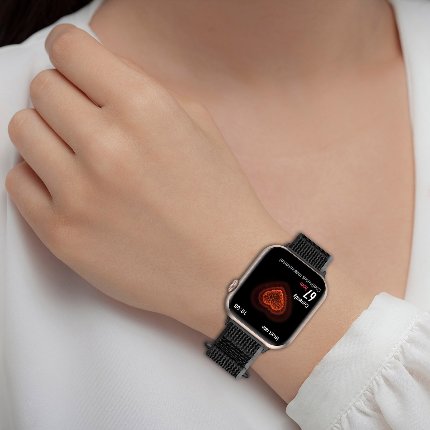Handgelenk einer Frau mit Smartwatch, Herzfrequenzanzeige, schwarzes Armband, weißer Hintergrund.