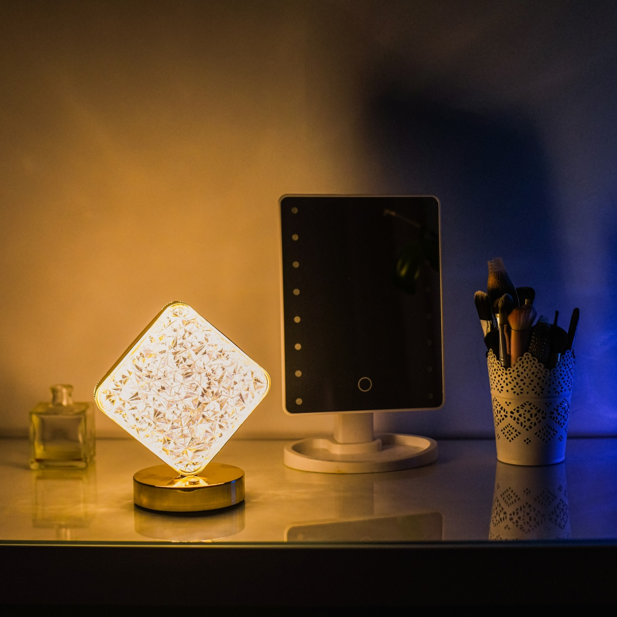 Tocador con espejo iluminado, lámpara y brochas de maquillaje.