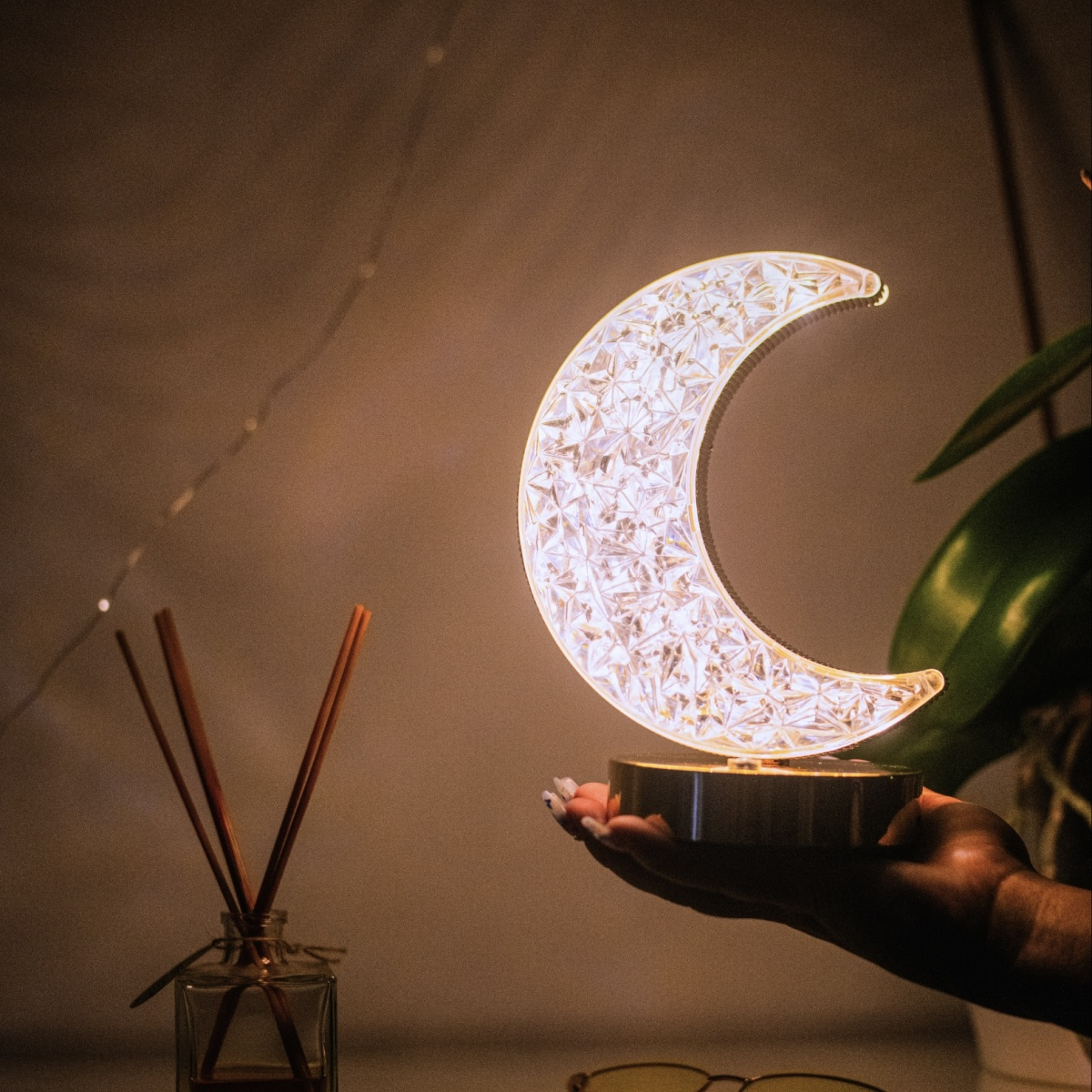 Una mano sostiene una lámpara de luna creciente brillante.