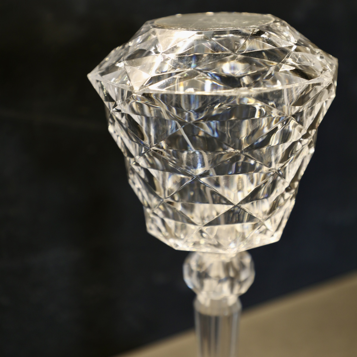 Primer plano de candelabro de cristal, transparente, con fondo oscuro, detalles de cortes de vidrio.
