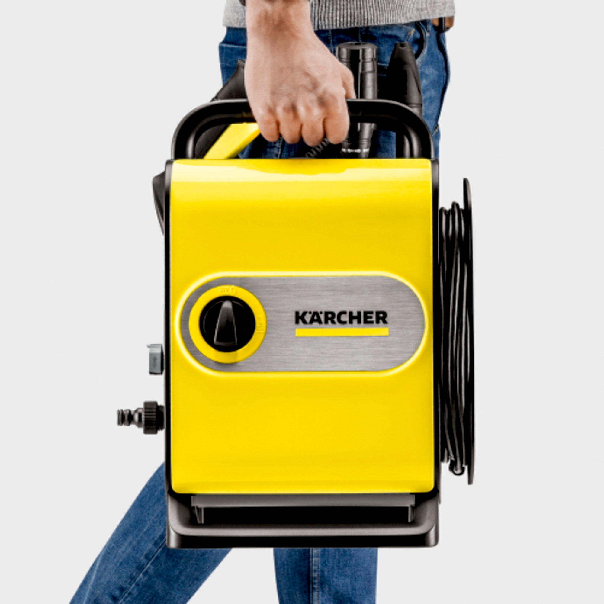 Een persoon die een gele Kärcher hogedrukreiniger vasthoudt, met de merknaam zichtbaar.