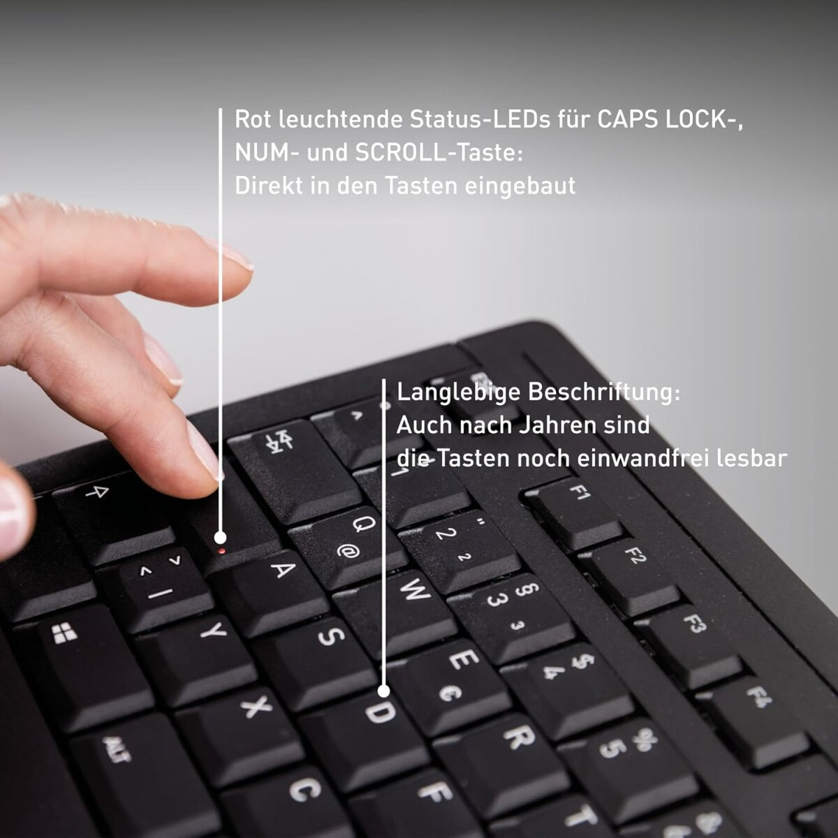 Mano presionando una tecla en un teclado negro. El indicador de bloqueo de mayúsculas rojo está encendido.