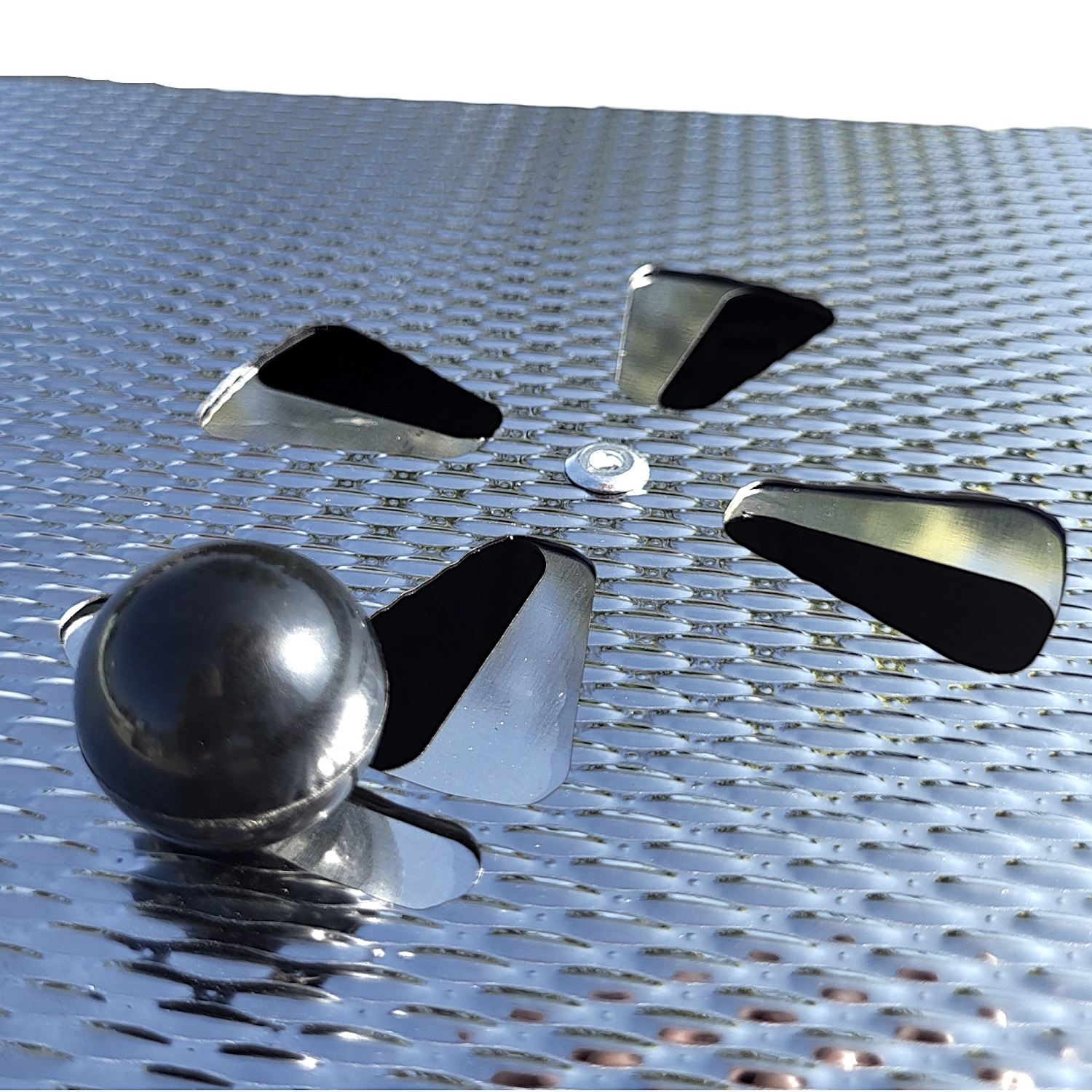Metallteile, darunter vier winklige Formen, ein zentrales rundes Objekt und eine dunkle, glänzende Kugel.