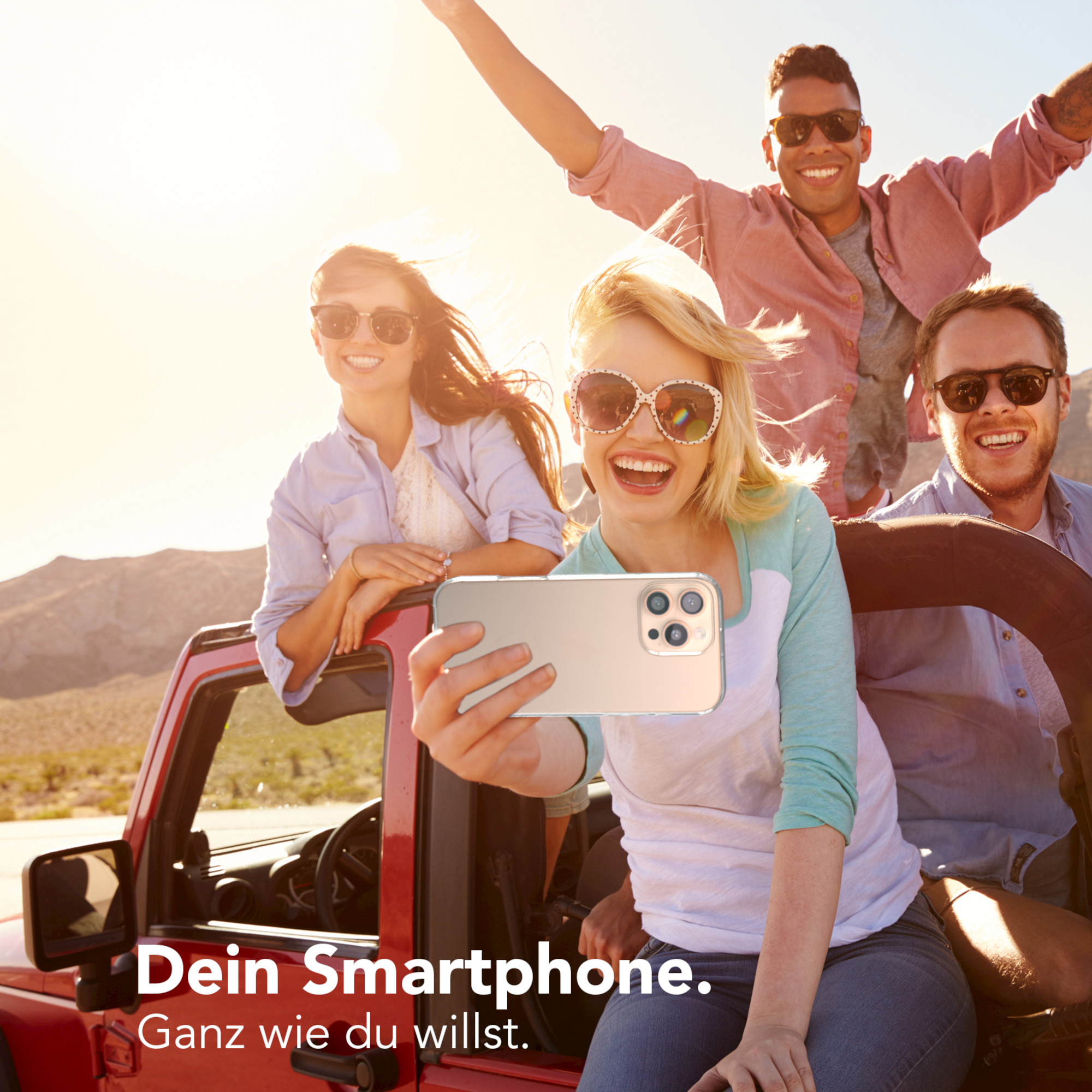 Vier Personen machen ein Selfie in einem roten Jeep, lächeln in die Kamera an einem sonnigen Tag.