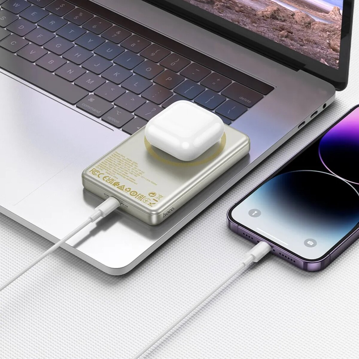 Telefono in carica su un caricatore wireless su un laptop. Custodia AirPods sopra.
