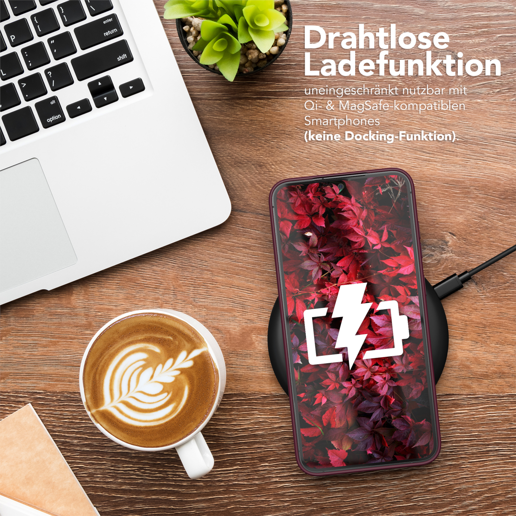 Ein Telefon mit Ladeanzeige auf einem kabellosen Ladegerät. Eine Tasse Kaffee und ein Laptop sind ebenfalls sichtbar.