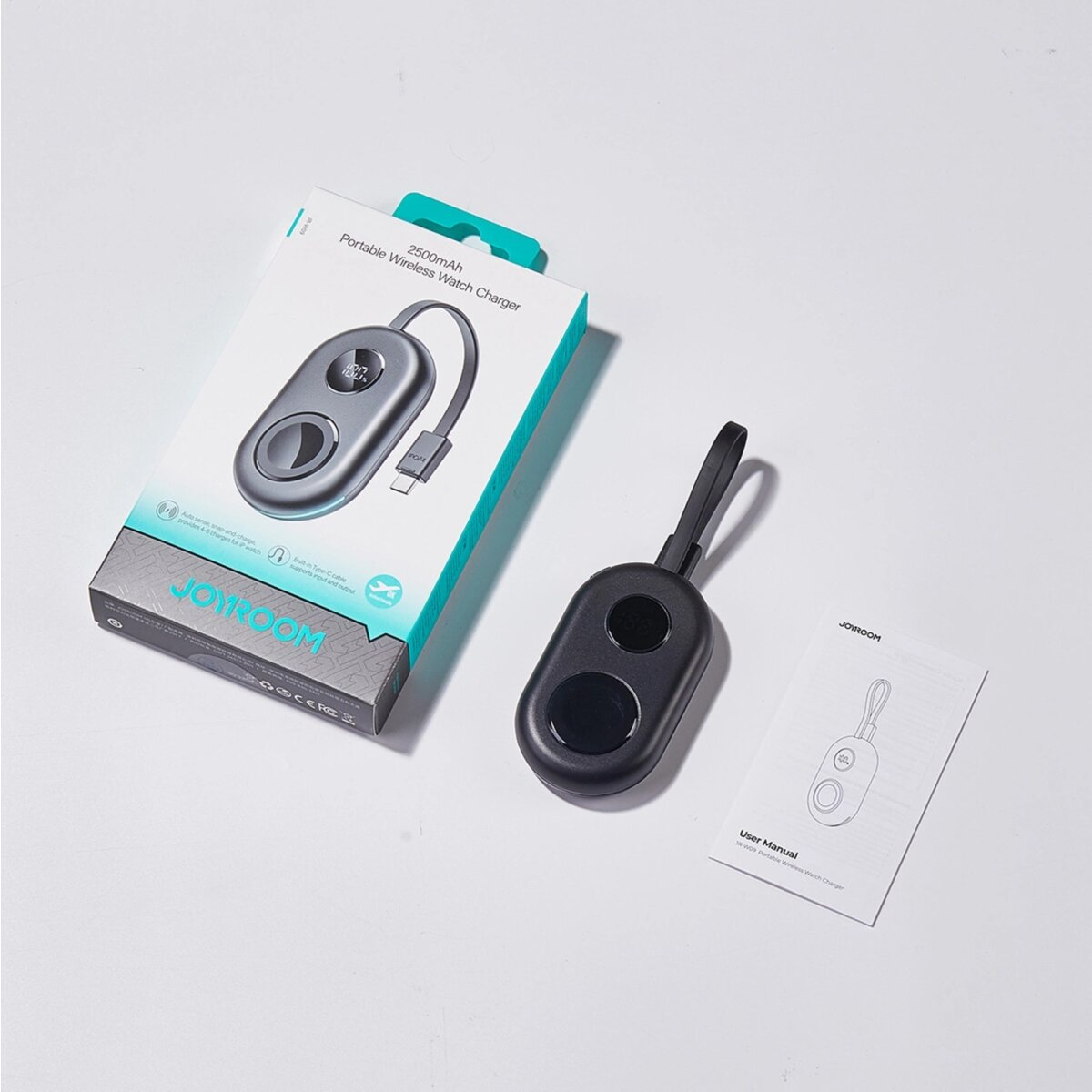 Przenośna bezprzewodowa ładowarka do zegarka z pudełkiem, ładowarką i instrukcją obsługi na białym tle.