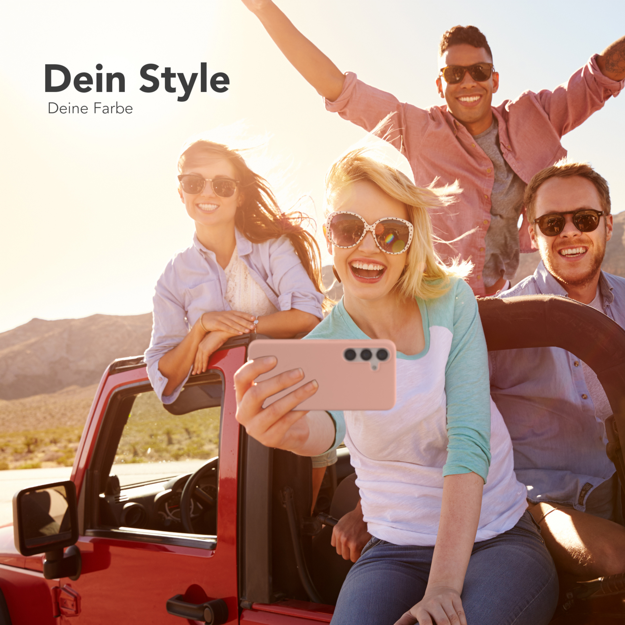 Vier Personen in einem roten Jeep machen ein Selfie. Sie lächeln. Im Hintergrund scheint die Sonne.