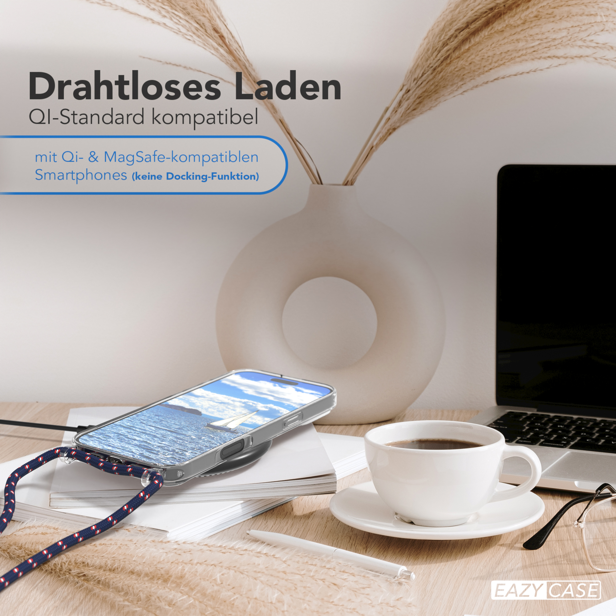 Telefon auf kabellosem Ladegerät, Kaffeetasse und Brille auf einem Tisch. Zwei Pampasgrasstiele.
