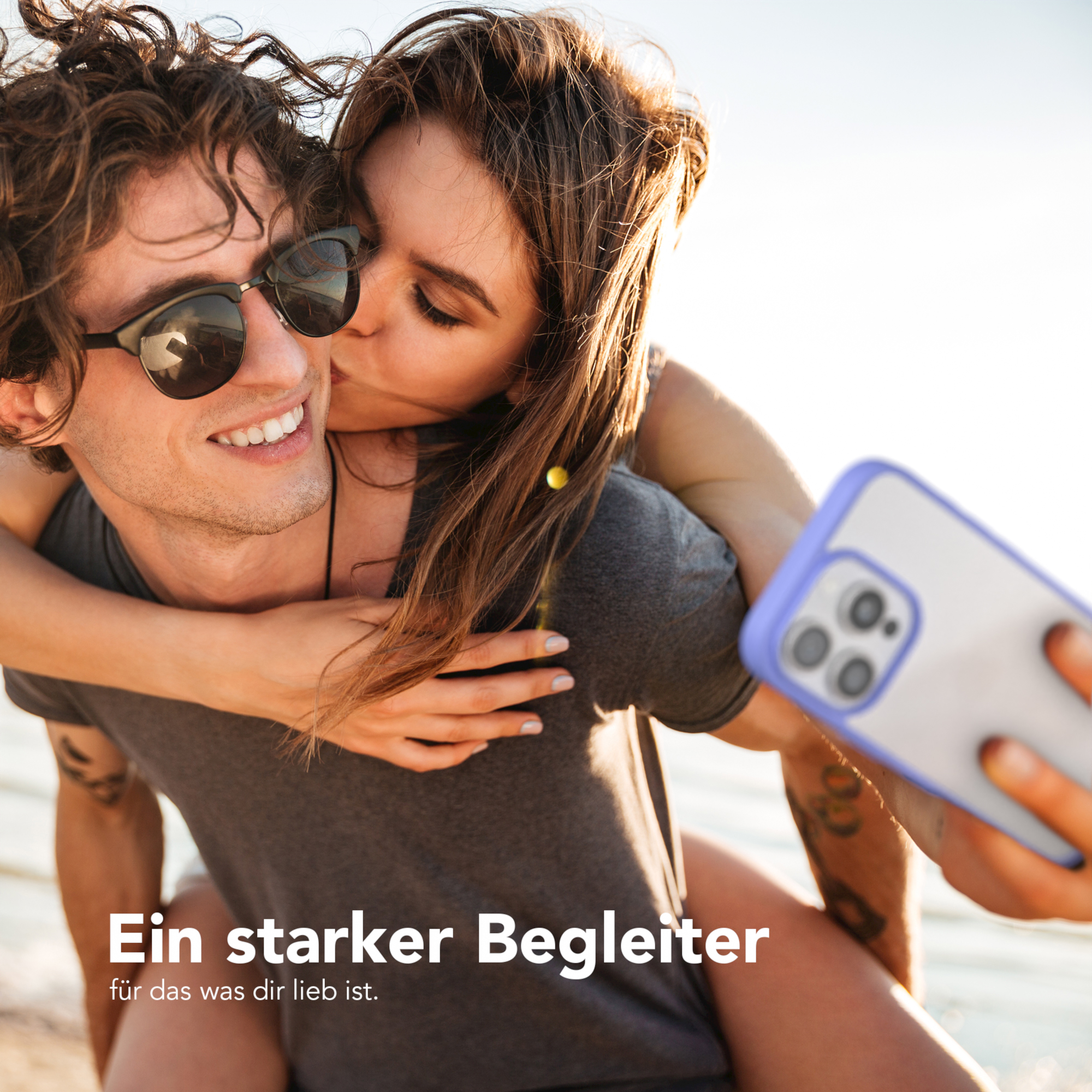 Frau küsst Mann auf die Wange, während er ein Telefon hält. Text: Ein starker Begleiter.