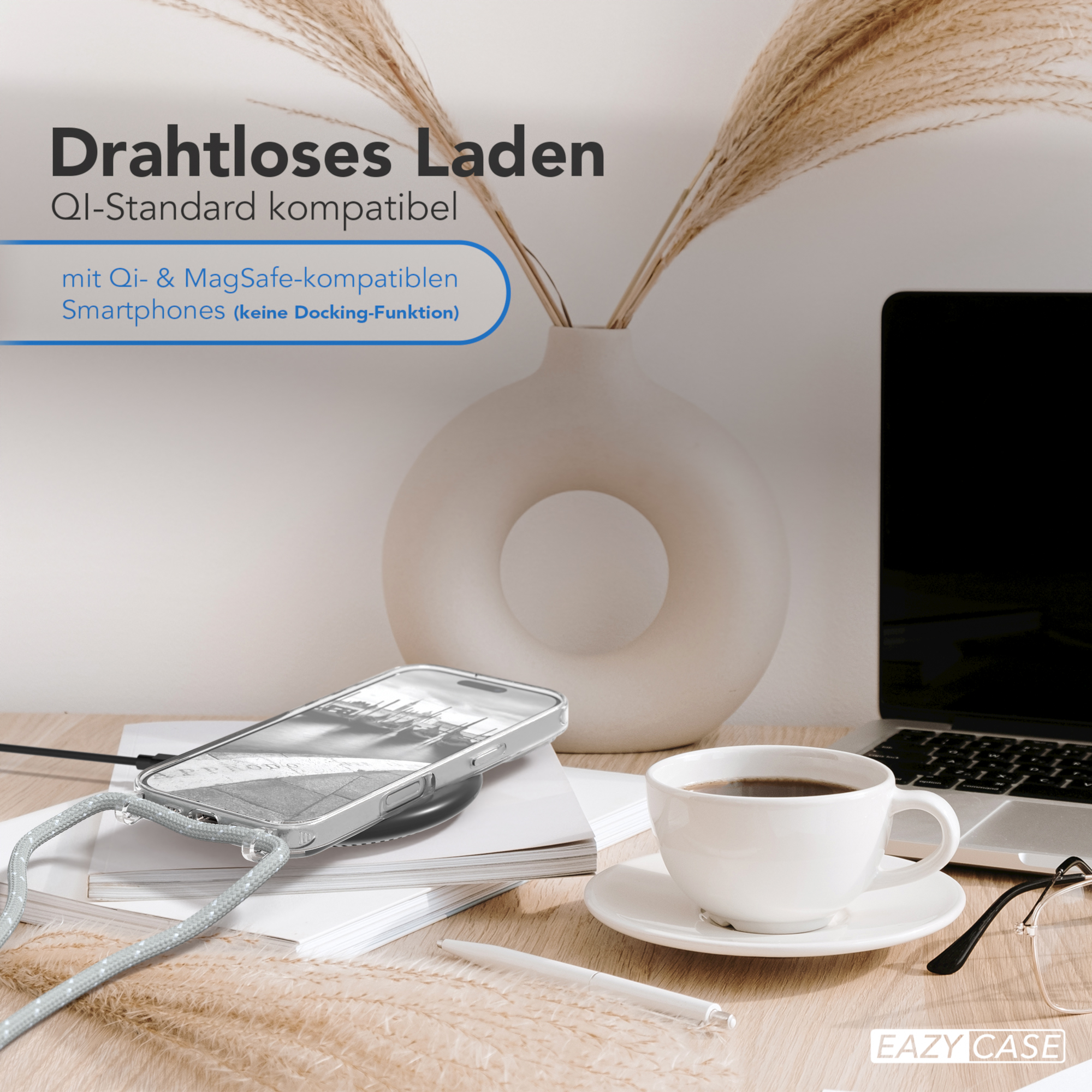 Telefon in Hülle auf dem Schreibtisch. Kaffee und Laptop, Blumenvase. Kabelloses Ladegerät.